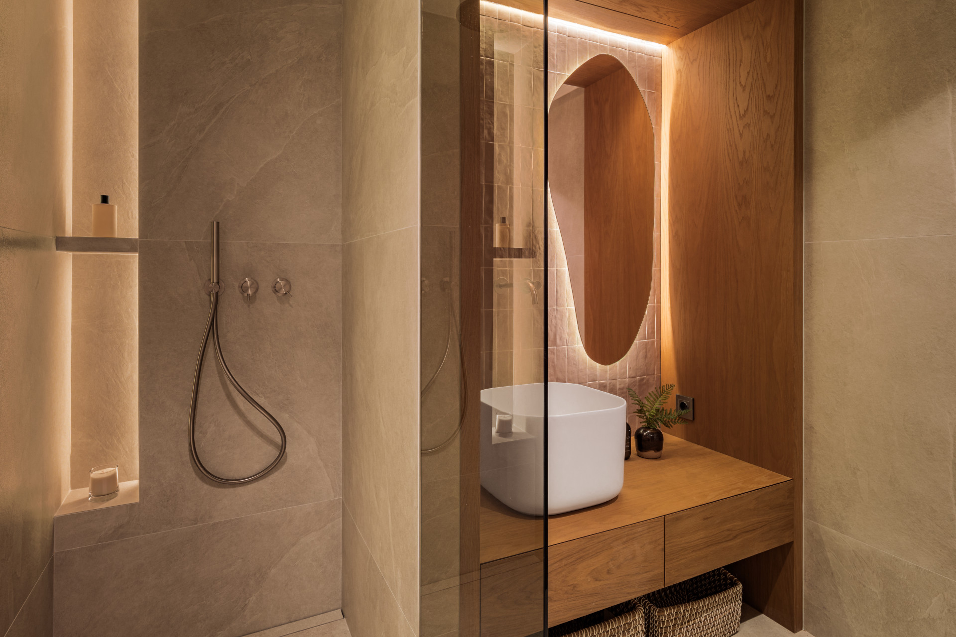 Reflected view of a bathroom vanity with a white sink and shower with recessed lighting.