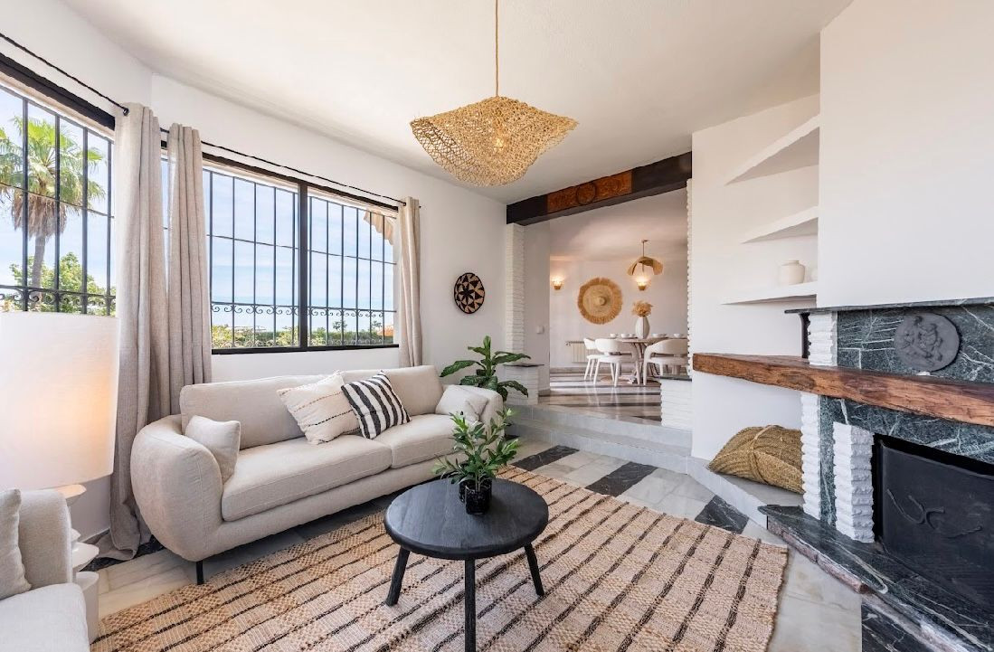 Living room with a sofa, fireplace, and view into an elevated dining area with a round table.