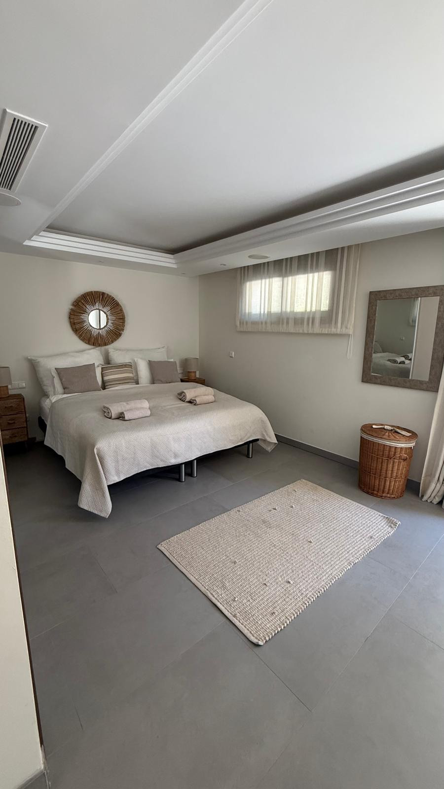 Cozy bedroom with a double bed, bedside tables, a mirror, and natural light from a window.