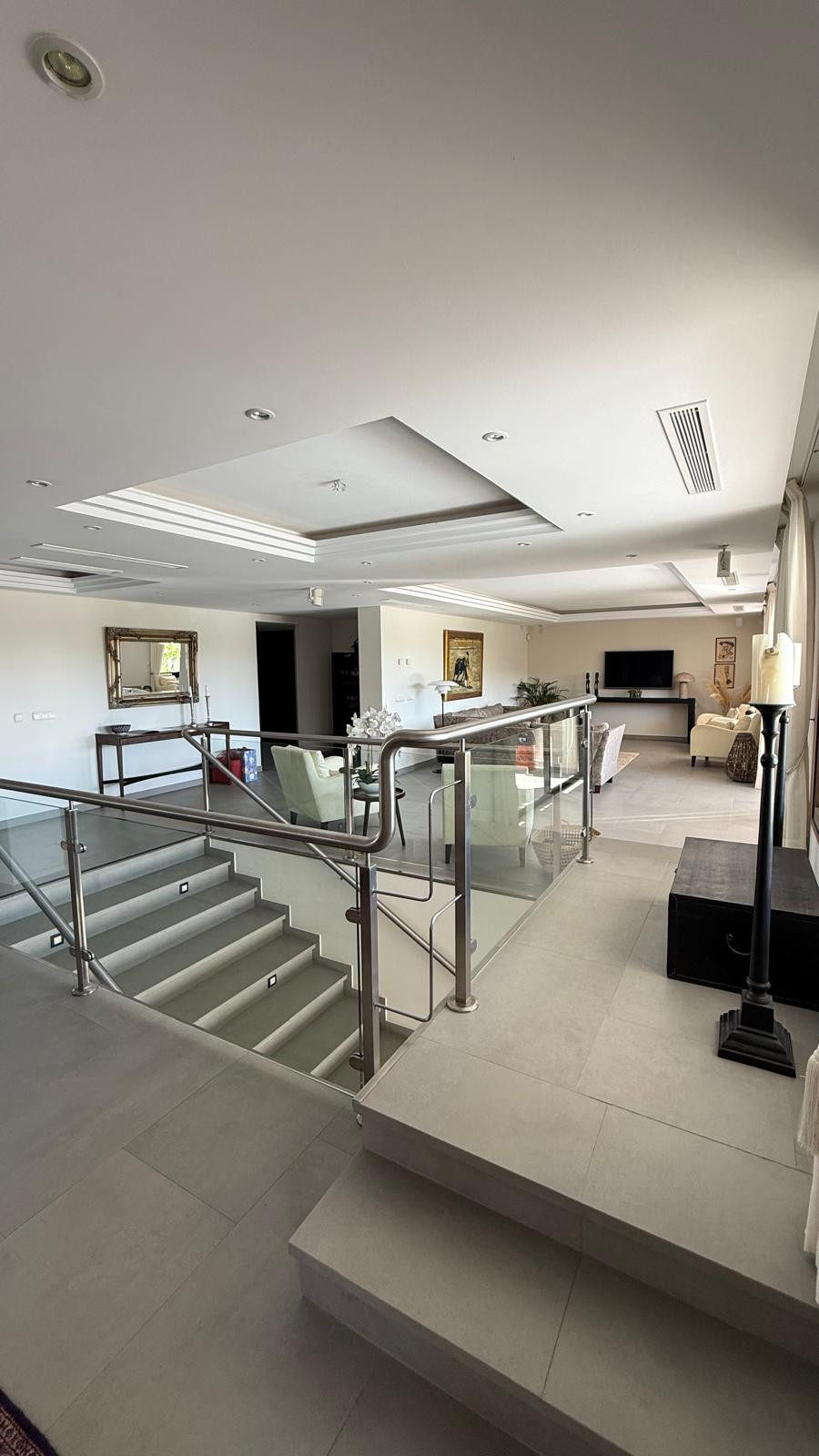 Modern foyer with stairs leading to living space, illuminated by recessed lighting and decor on walls.