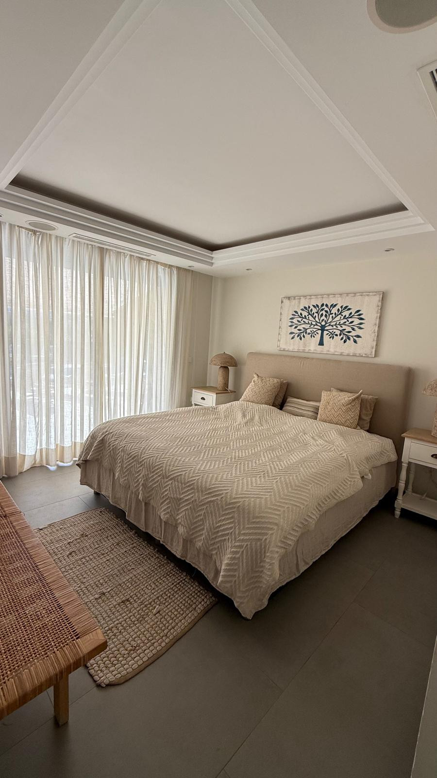 Cozy bedroom with a king-sized bed, large windows, and soft curtains.