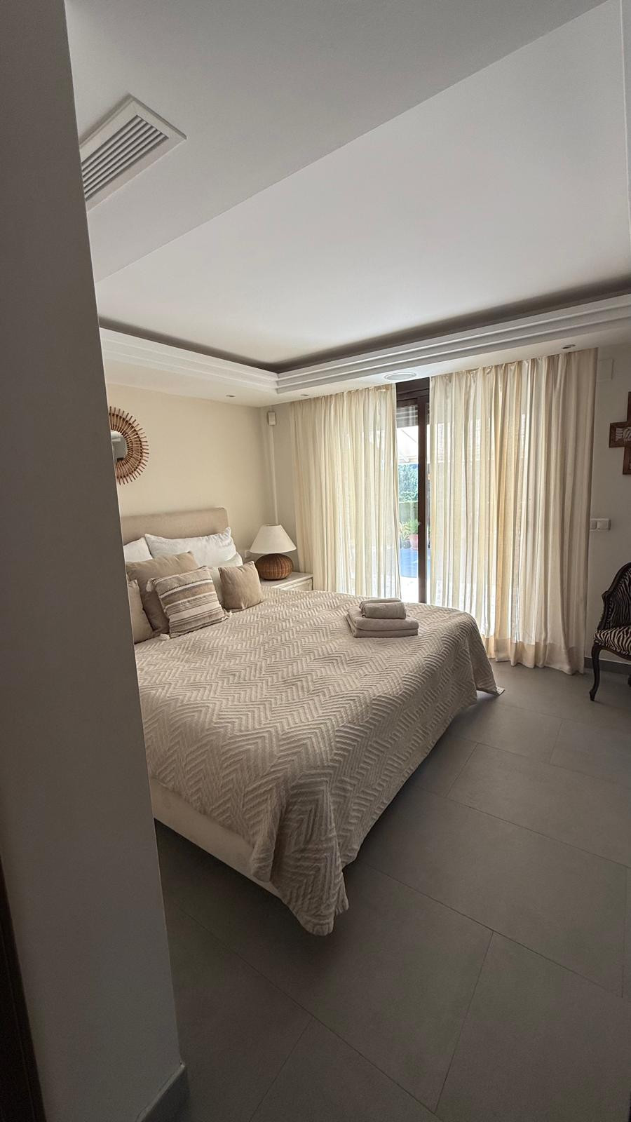 Inviting bedroom with a king-sized bed, large windows, and soft fabrics.