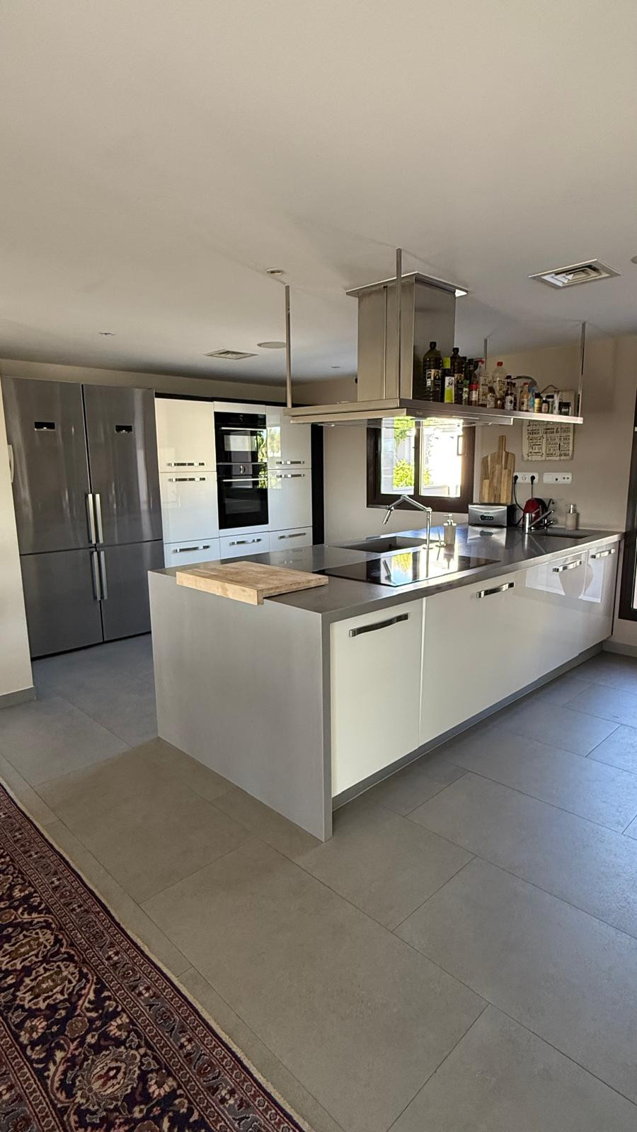Modern kitchen with grey and white cabinetry, stainless steel appliances, and a workspace.
