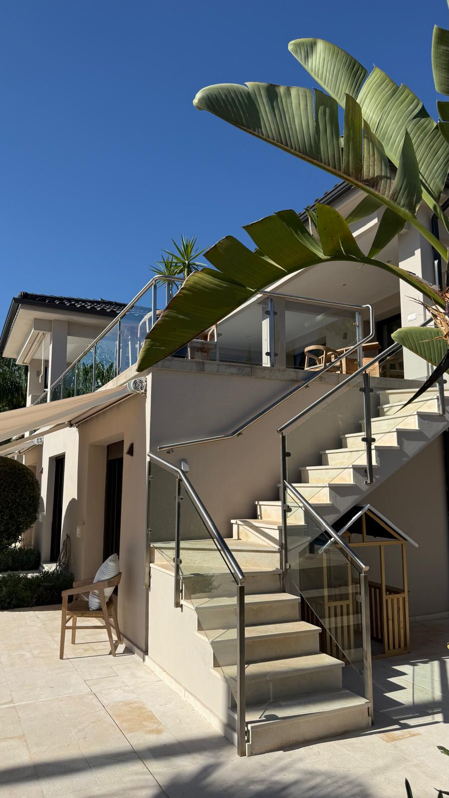 View of stairs leading to upper deck with glass railing and lush greenery.