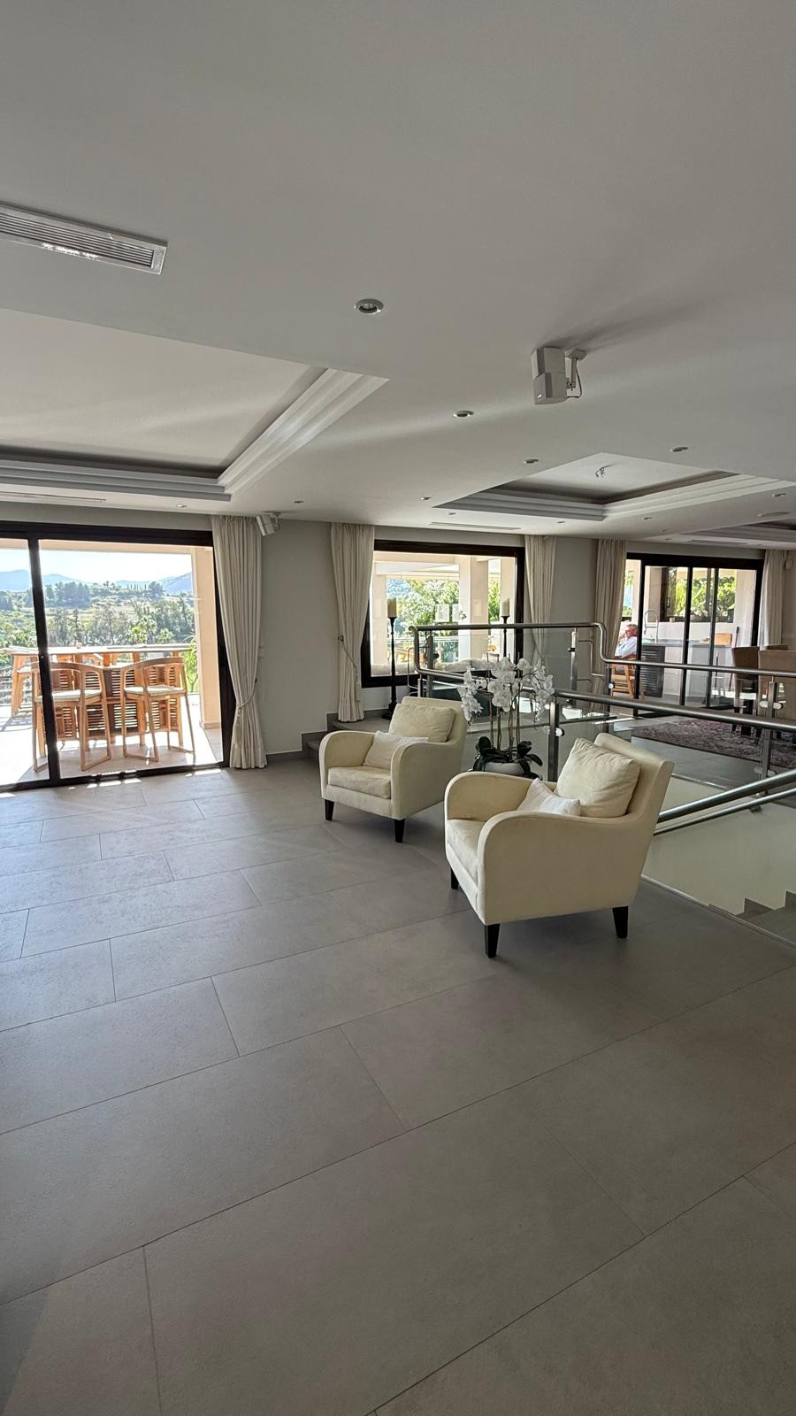 Bright living room space with two chairs and large glass doors offering access to an outdoor terrace.