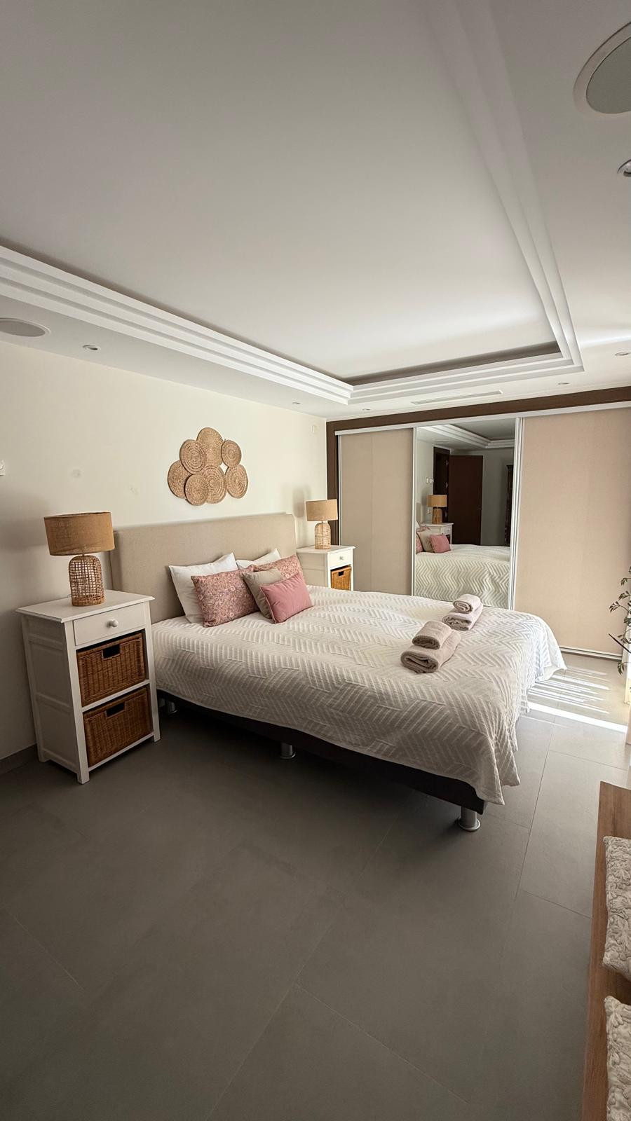 Cozy bedroom featuring a king bed, two lamps, and a wall decor element above the headboard.