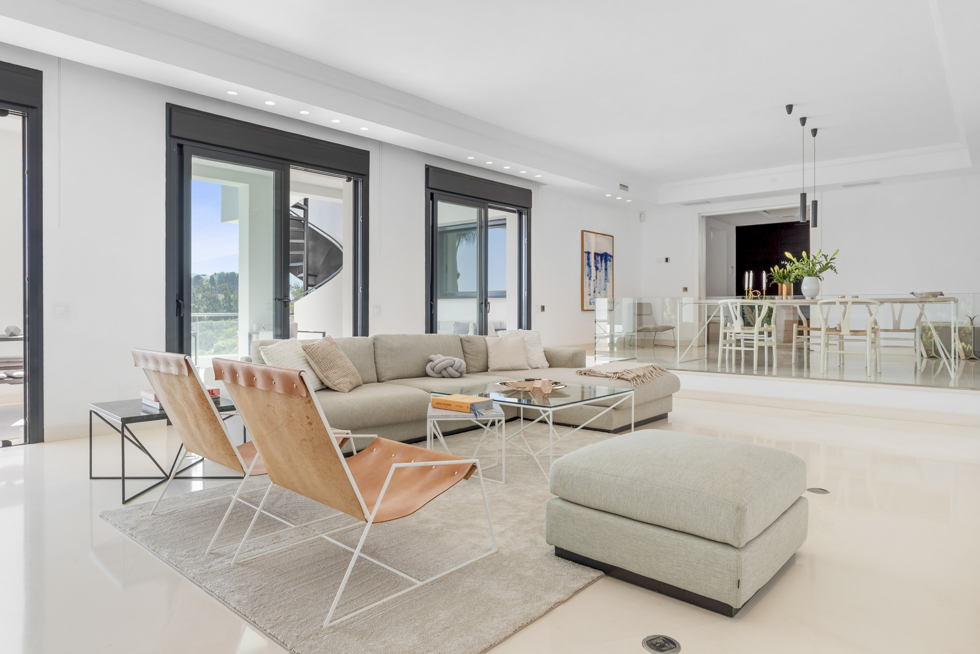 Open living area with cozy seating, a clear view of the spiral staircase, and light streaming through glass doors.