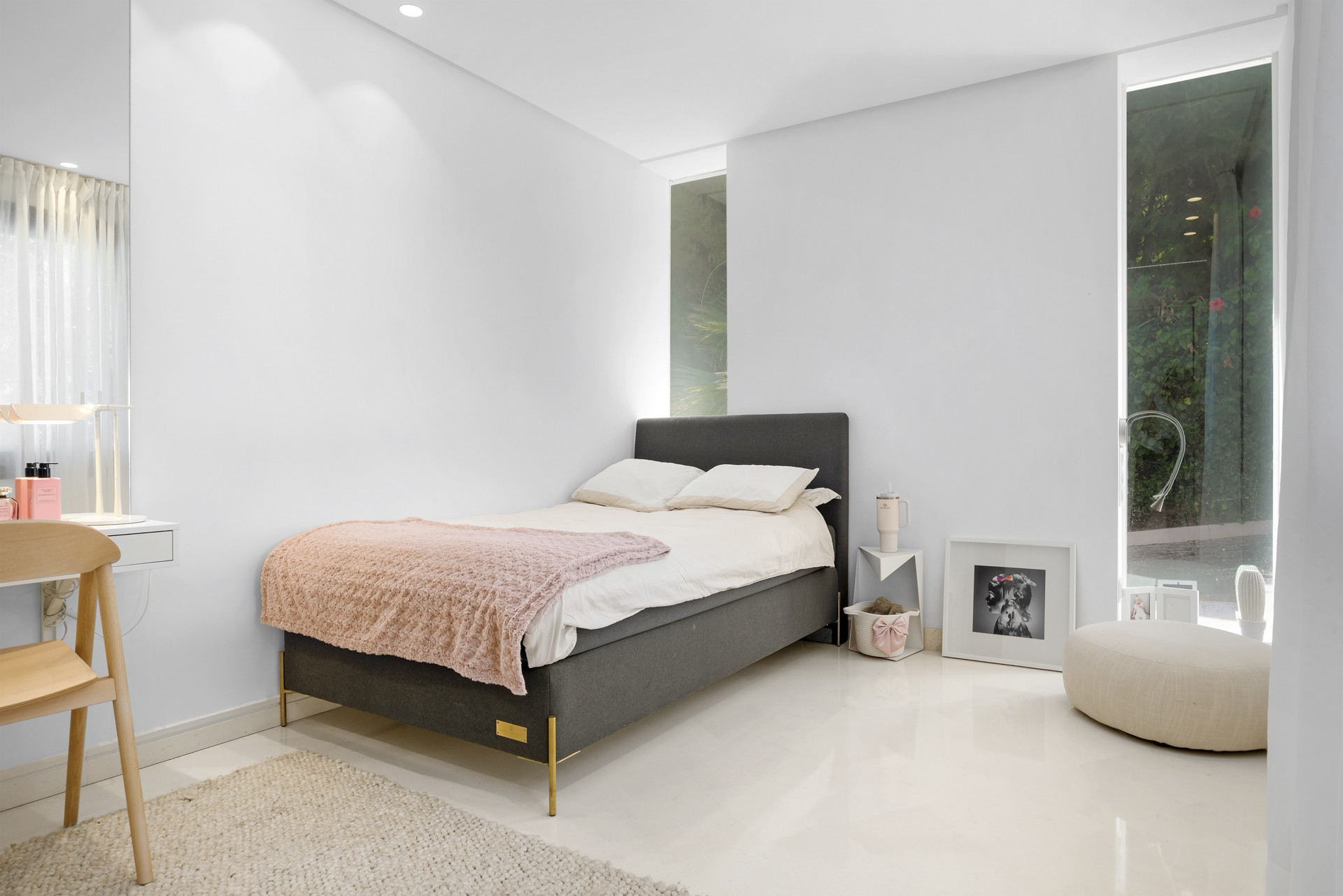 Cozy bedroom featuring a grey bed and bright natural light through large windows.