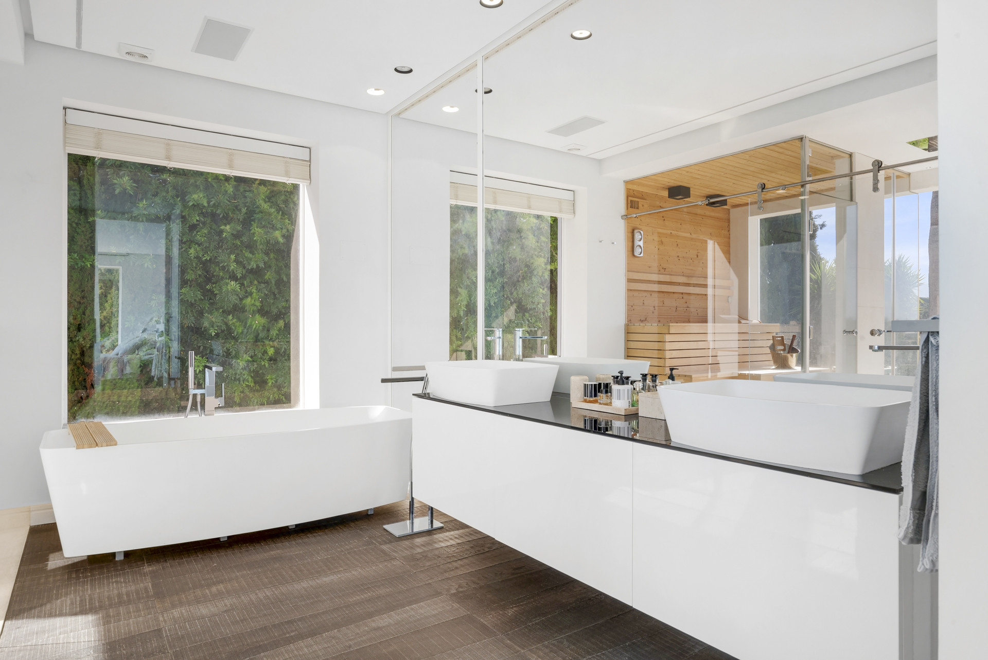 Stylish bathroom featuring double sinks, modern freestanding tub, and large mirrors with natural light.