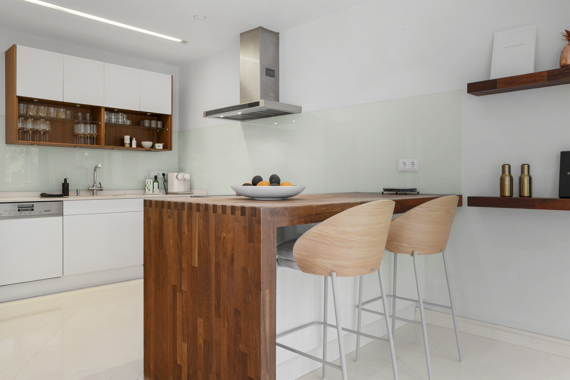 Stylish kitchen with white cabinets and a breakfast bar for seating, illuminated by overhead lights.