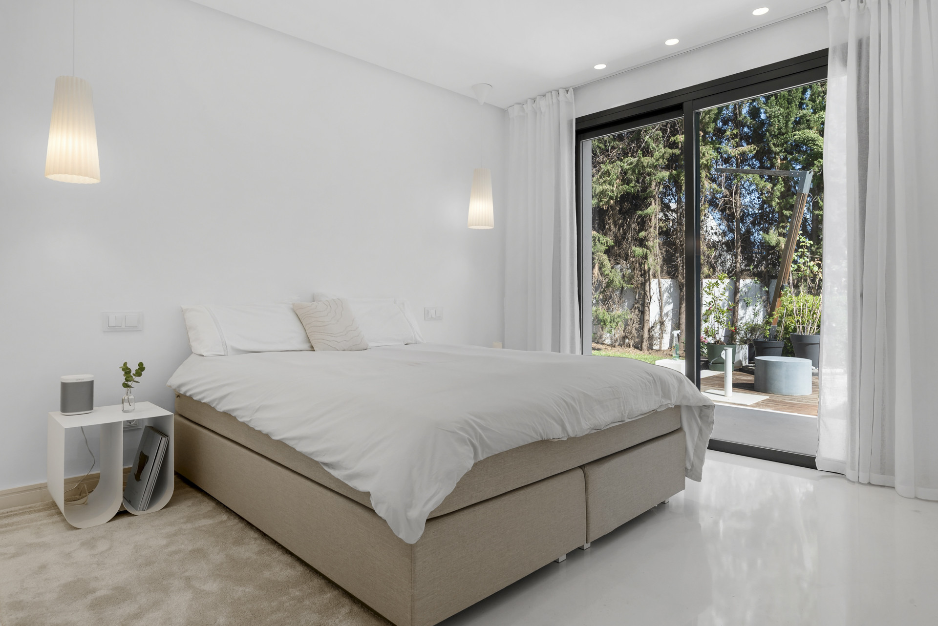 Spacious bedroom with a large bed, a side table, and sliding doors opening to an outdoor patio.