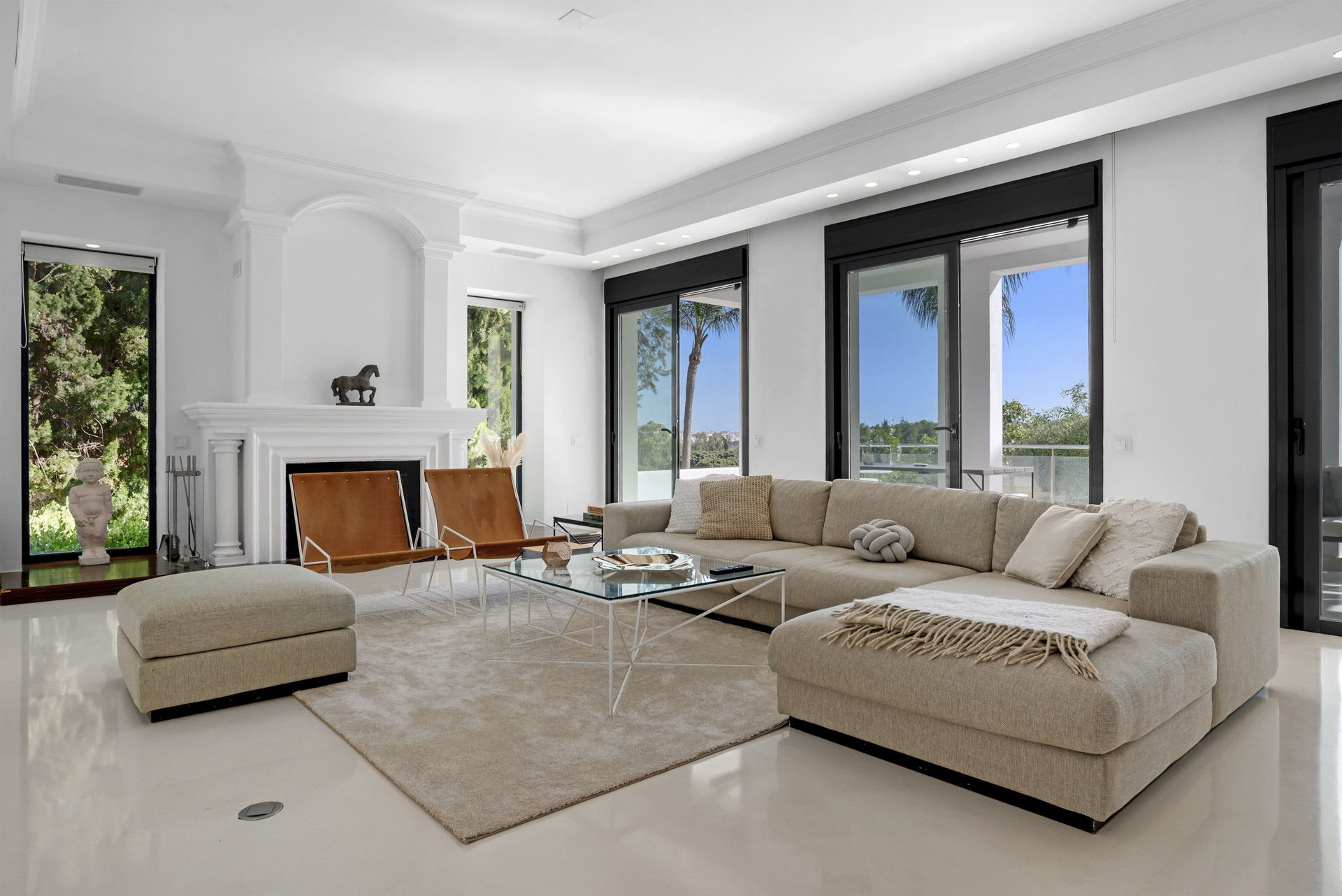 Cozy living space with a sectional sofa, coffee table, and decor elements like a fireplace and large windows.