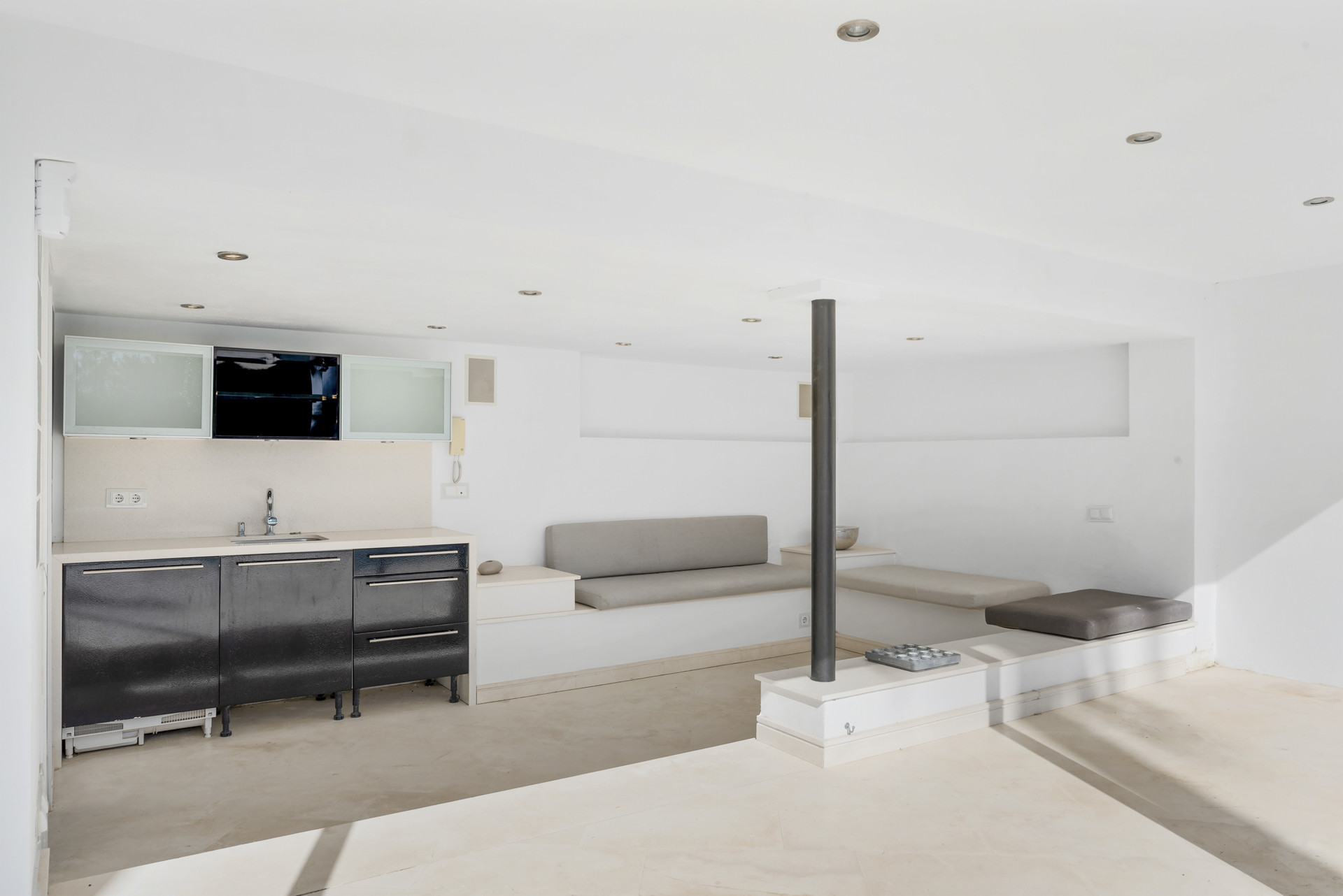 Minimalist interior with a small kitchen area and seating.