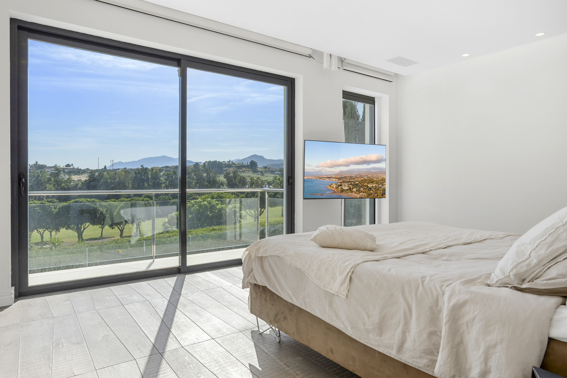 Bright bedroom with a bed and large glass doors opening to a balcony view.