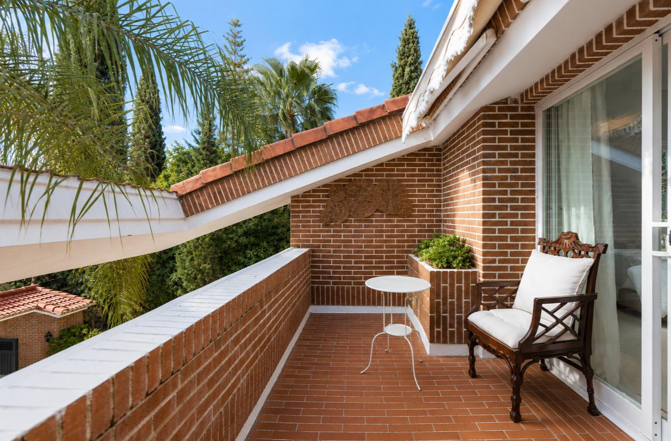 Outdoor terrace with seating and greenery under a clear blue sky.