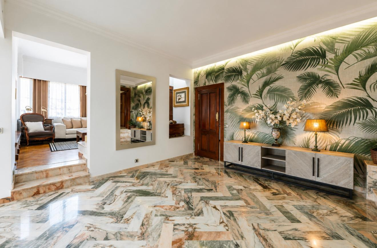 Elegant living area with patterned floor tiles and a tropical-themed wall.