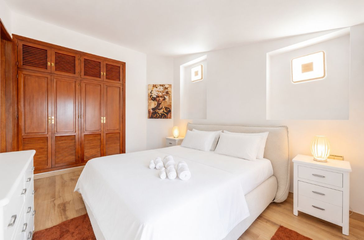 Bright bedroom showcasing a bed, artwork, and built-in closet.