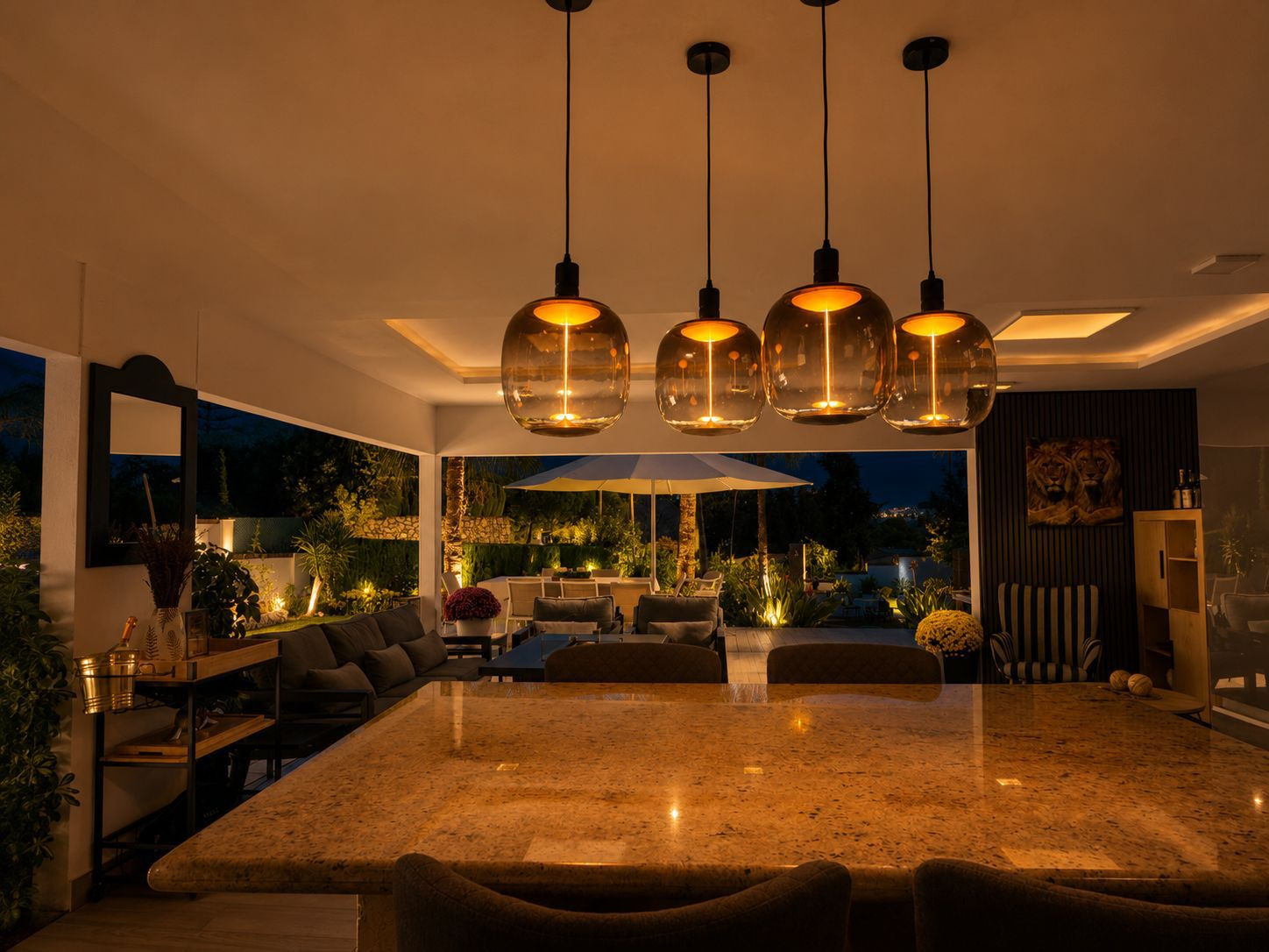 Well-lit outdoor dining area with stylish pendant lights at night.