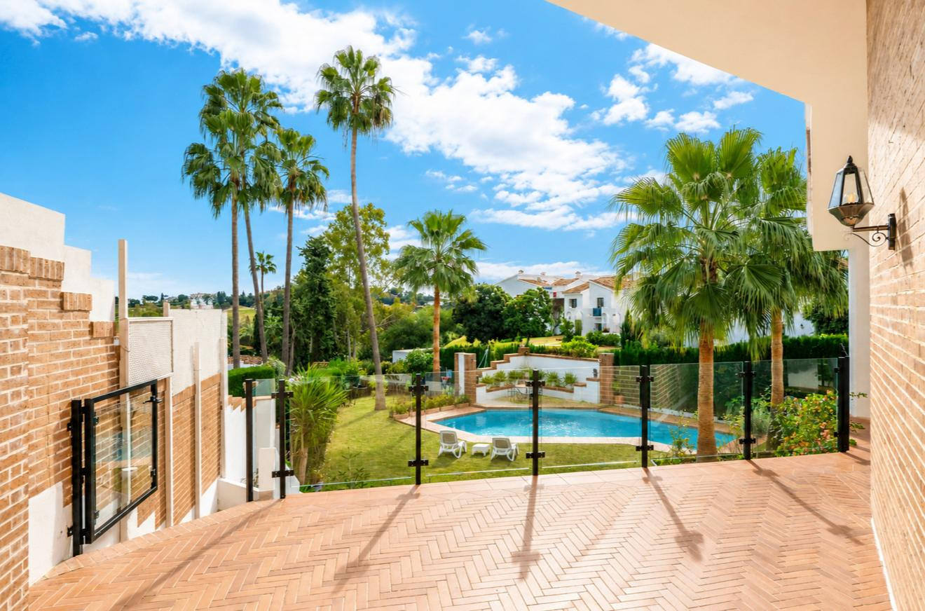 View from a balcony showcasing the pool surrounded by palm trees and greenery.