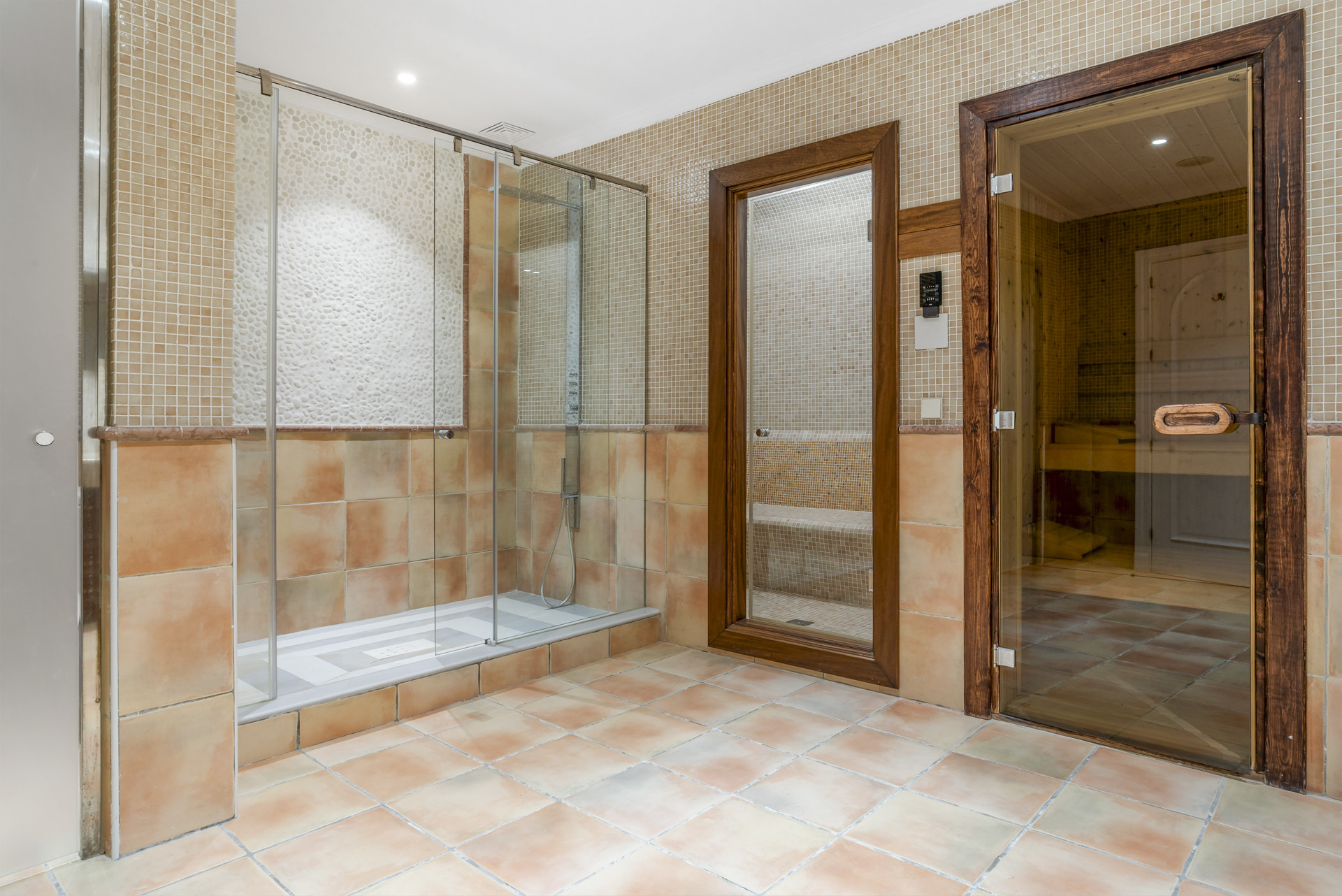 Spacious bathroom with shower, sauna room, and tile flooring.