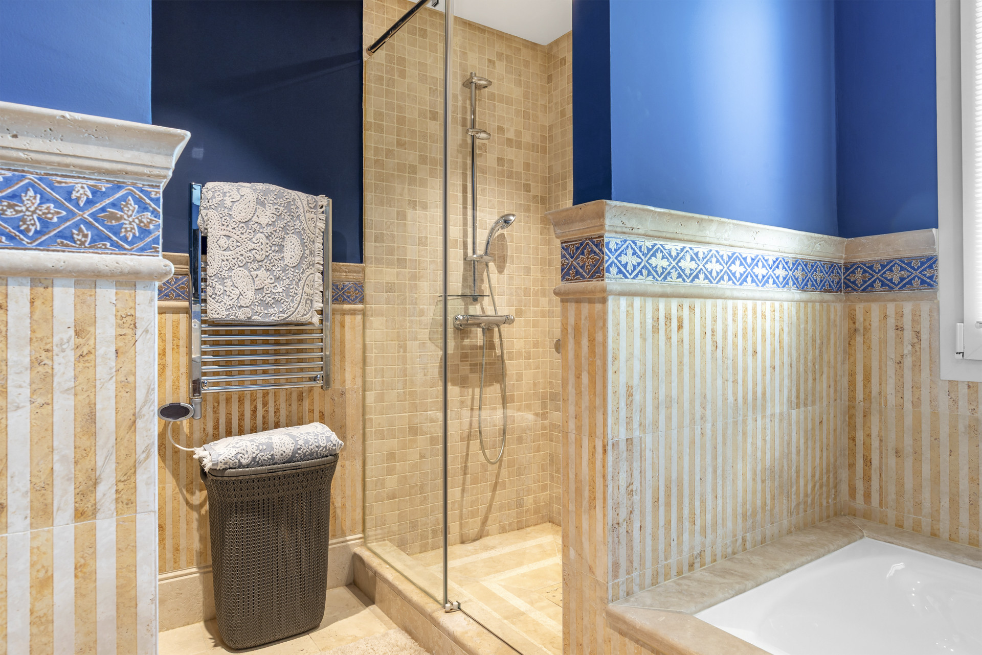 Modern bathroom with a walk-in shower, towel rack, and decorative tile accents.