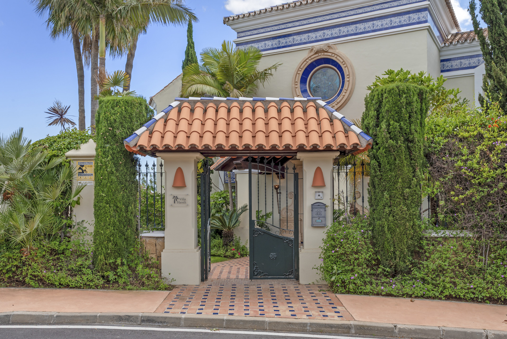 Gated entrance with a tiled roof and decorative garden features.