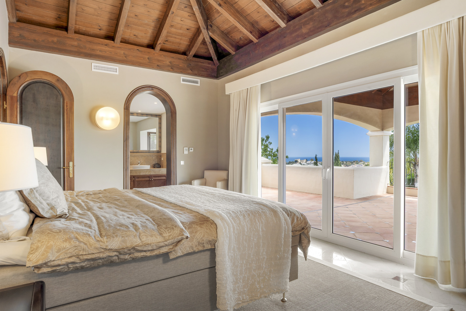 Bedroom featuring a wooden ceiling, plush bed, and sliding glass doors leading to a terrace.