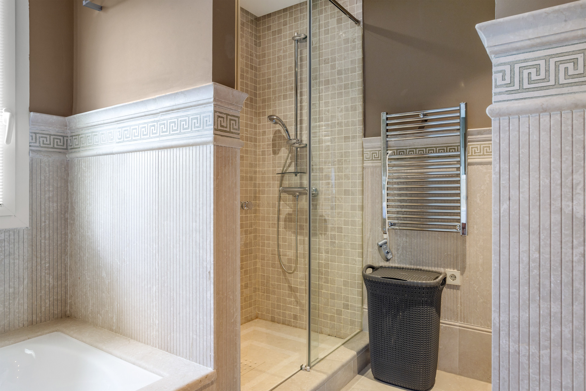 Shower area with glass walls, tiled accents, and heated towel rack.