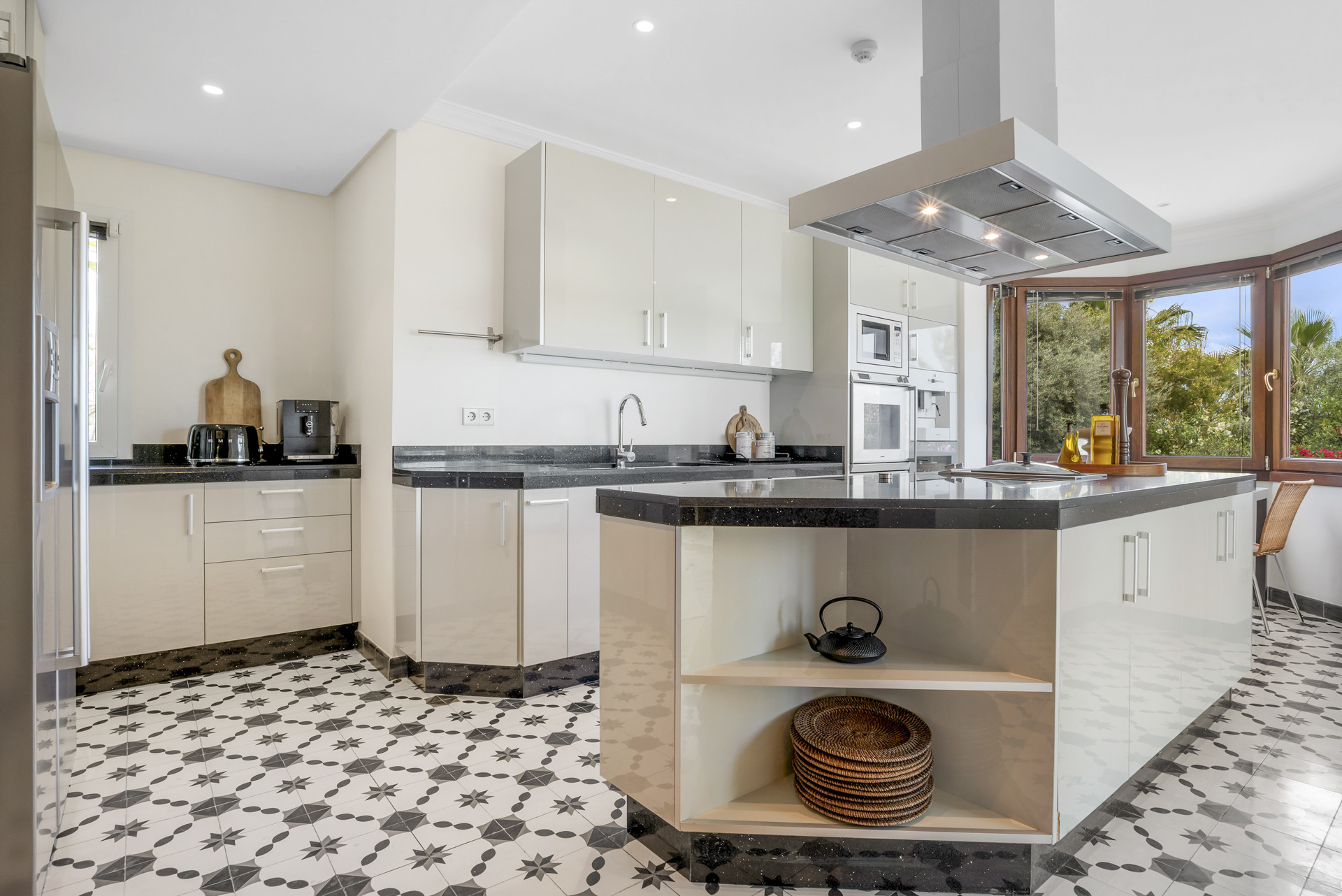 Bright kitchen with modern cabinetry, black countertops, and patterned tile flooring.