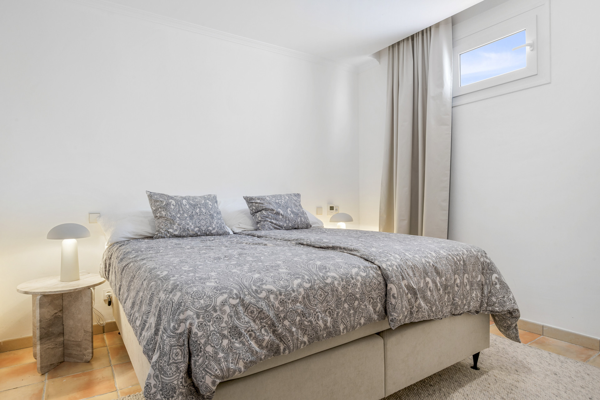 Bedroom featuring a double bed, patterned bedding, and window with natural light.