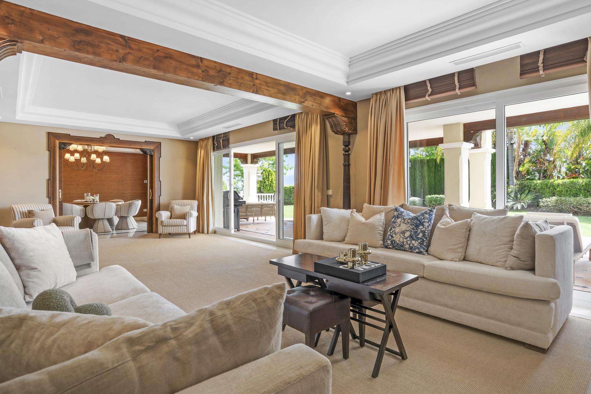 Spacious living area featuring two sofas, a dining space in the background, and a wooden beam.