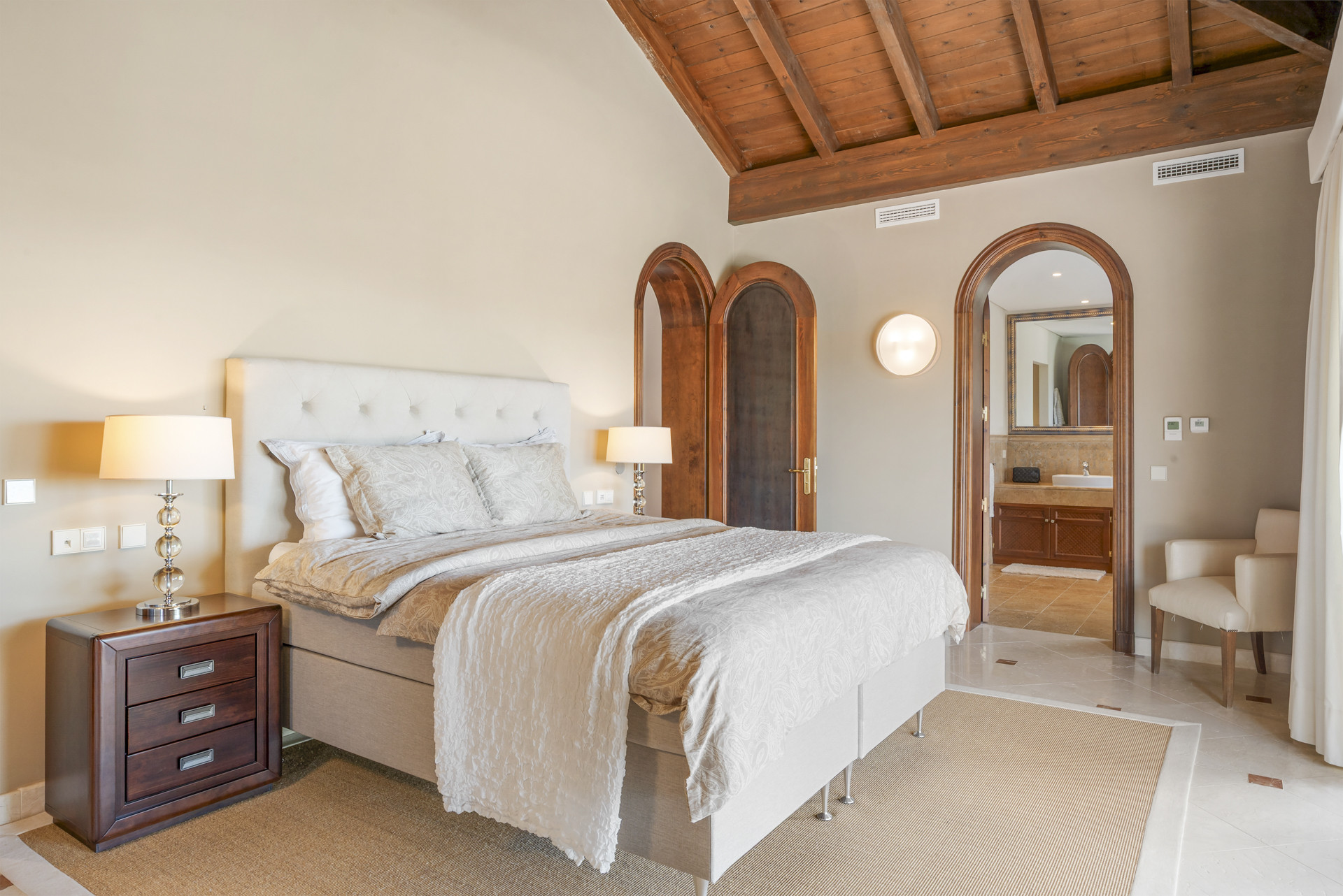 Master bedroom showcasing a bed, decorative pillows, and adjacent bathroom access.