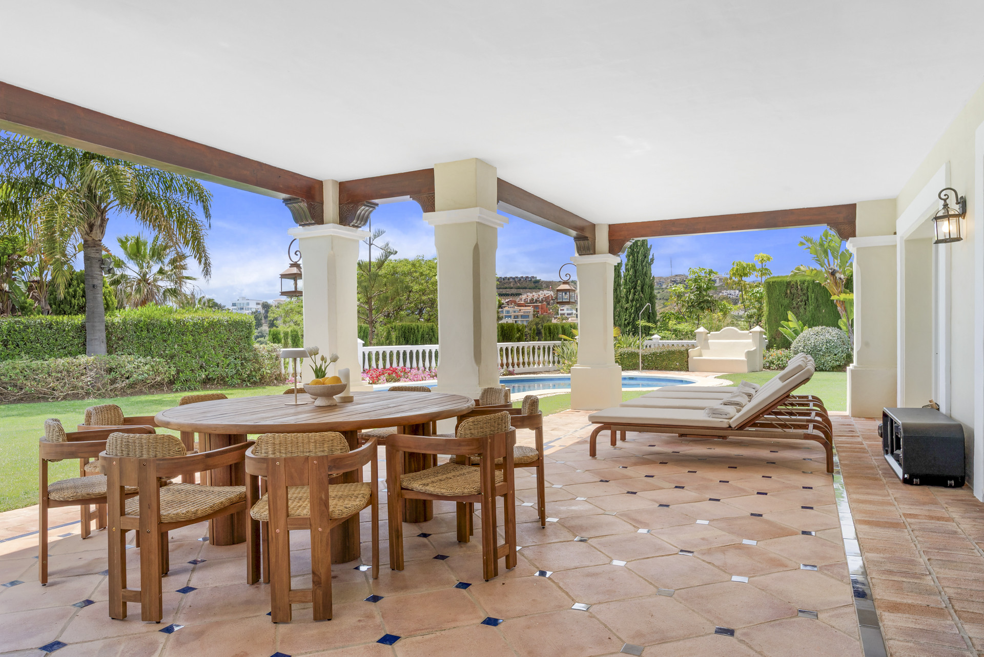 Covered terrace with a round dining table and lounge chairs, overlooking the garden.