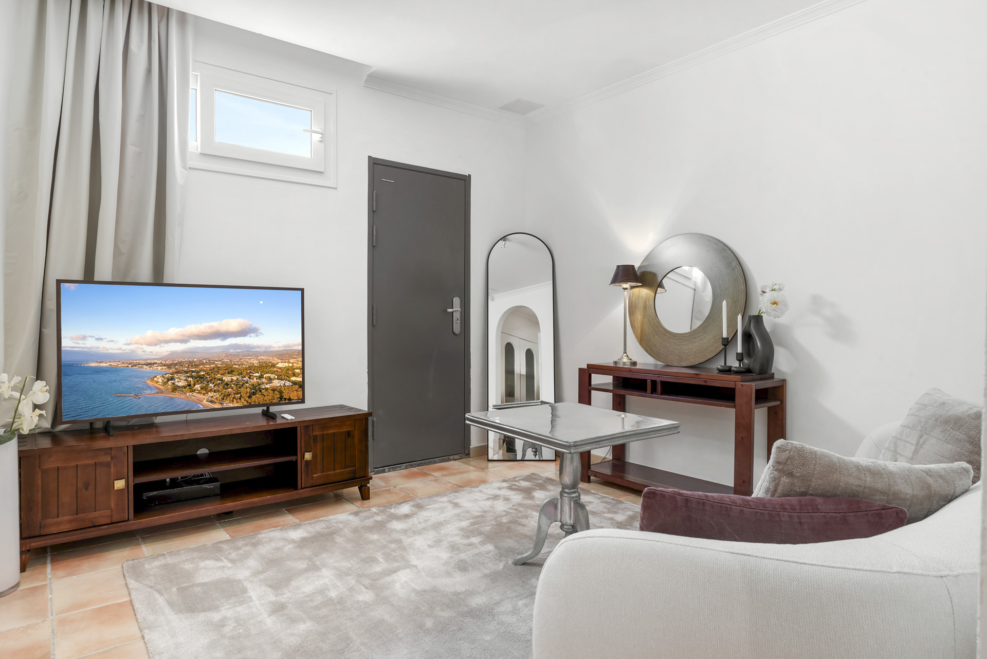 Living room with TV, decorative mirror, and a view outside.