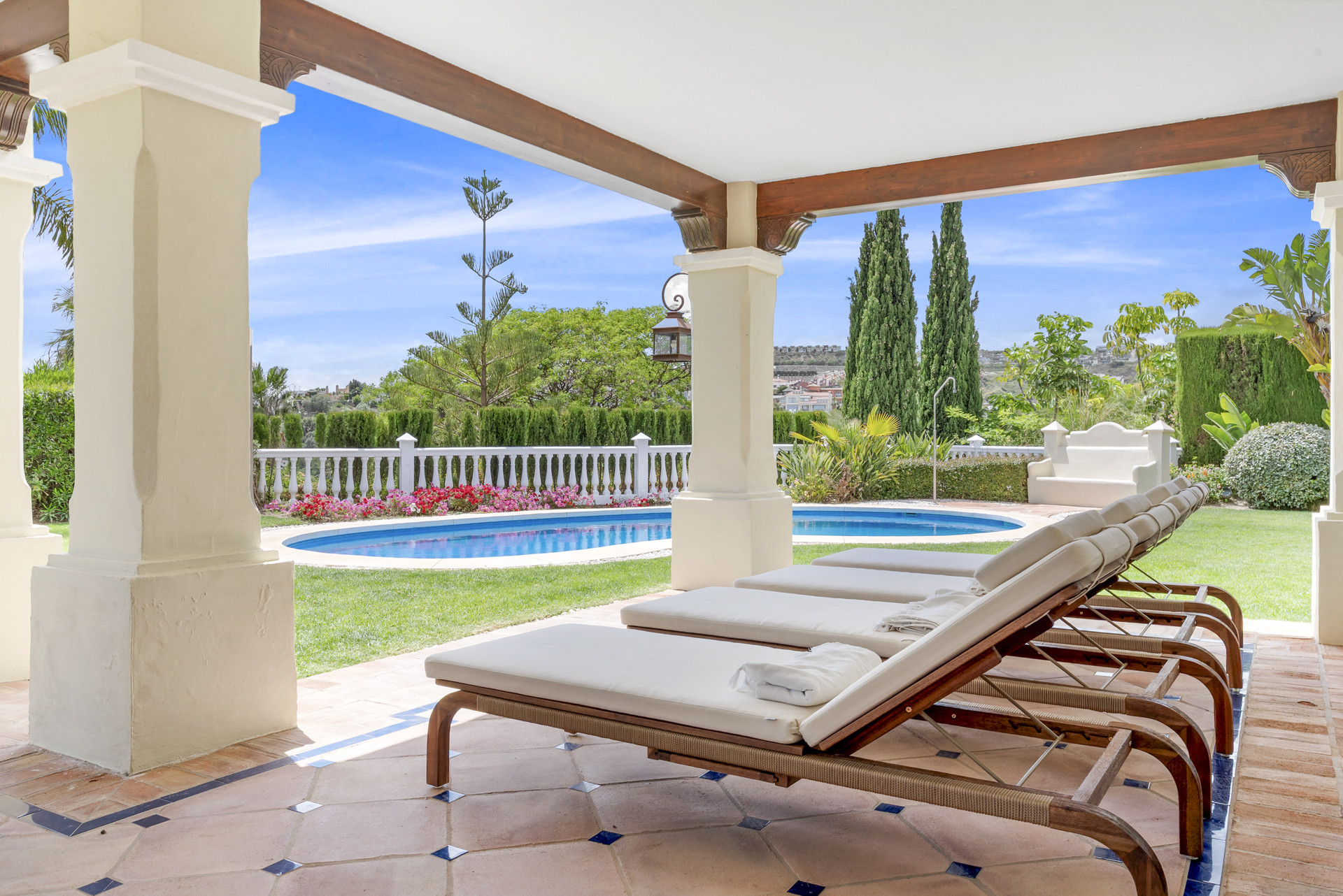 Lounge chairs arranged on the terrace, facing the garden and pool area.