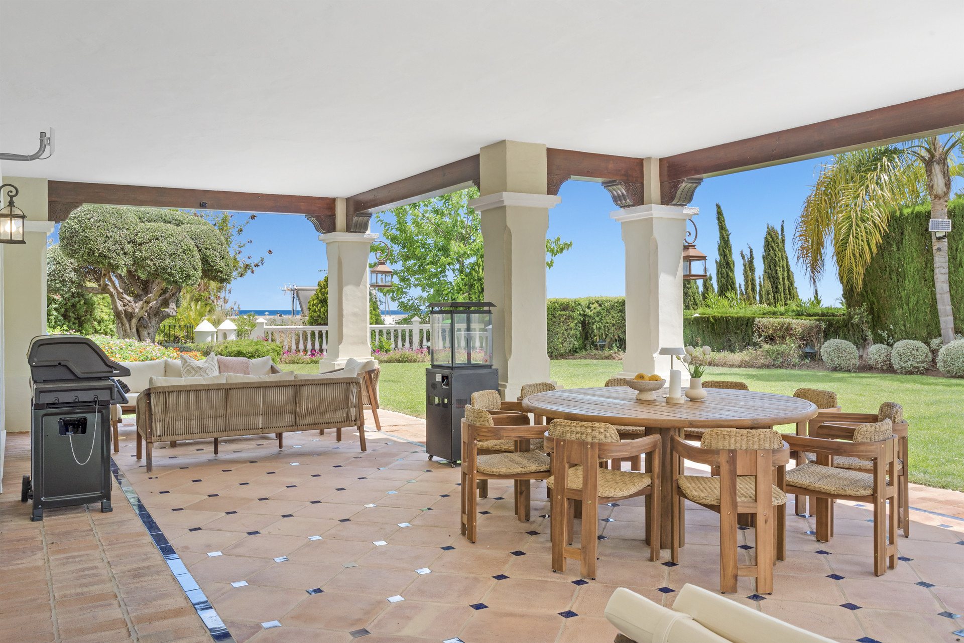 Outdoor dining area featuring a grill and a round table with sitting arrangements.