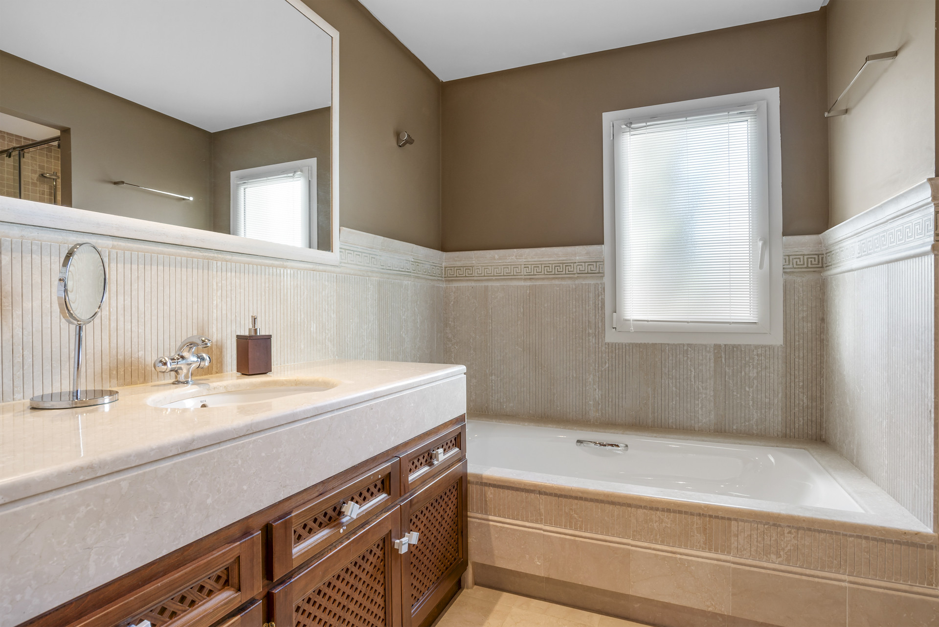 Modern bathroom with dual sinks, wooden cabinetry, and a bathtub.
