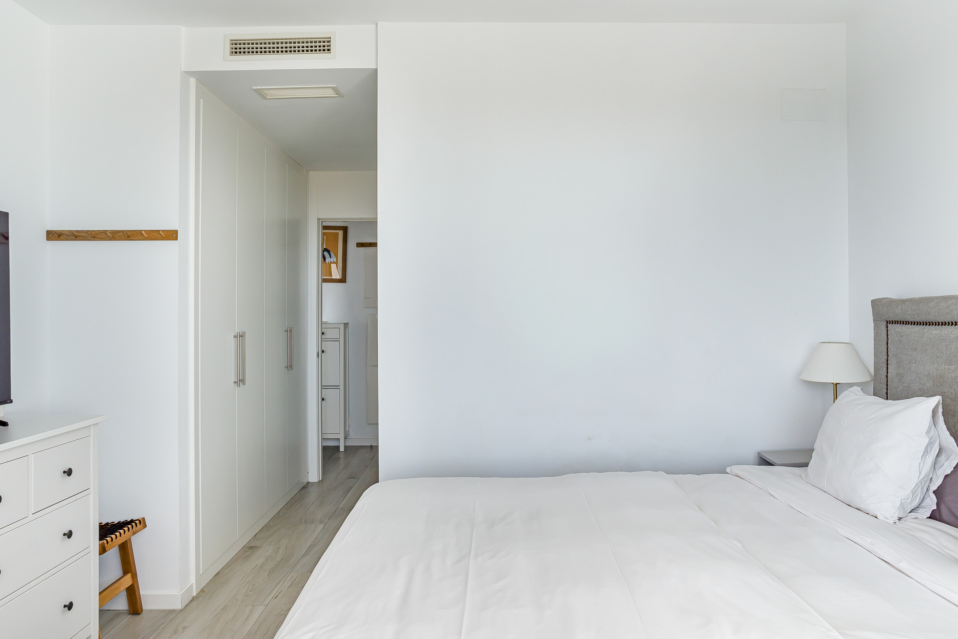 Bedroom with a bed, white built-in wardrobes, and an open doorway to another room.