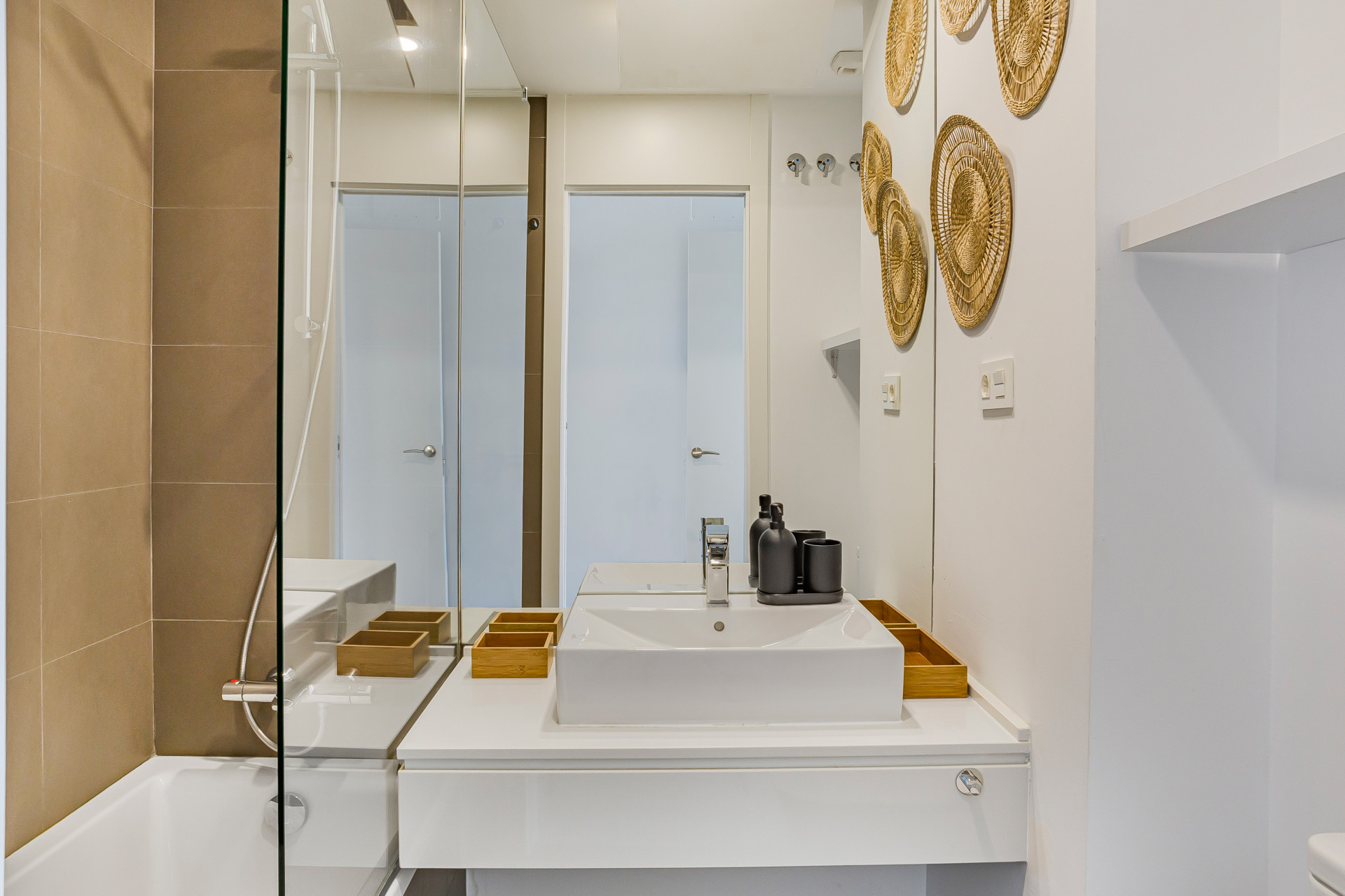 Bathroom with white vanity, sink, large mirror, shower-bath combo, and decorative wall art.