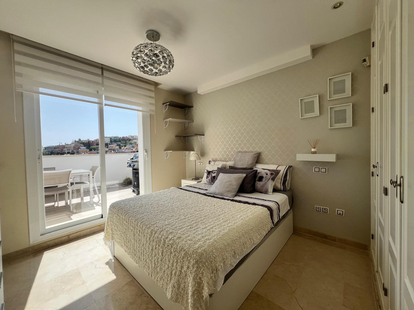 Bedroom with bed, patterned headboard wall, large glass sliding doors leading to a terrace.