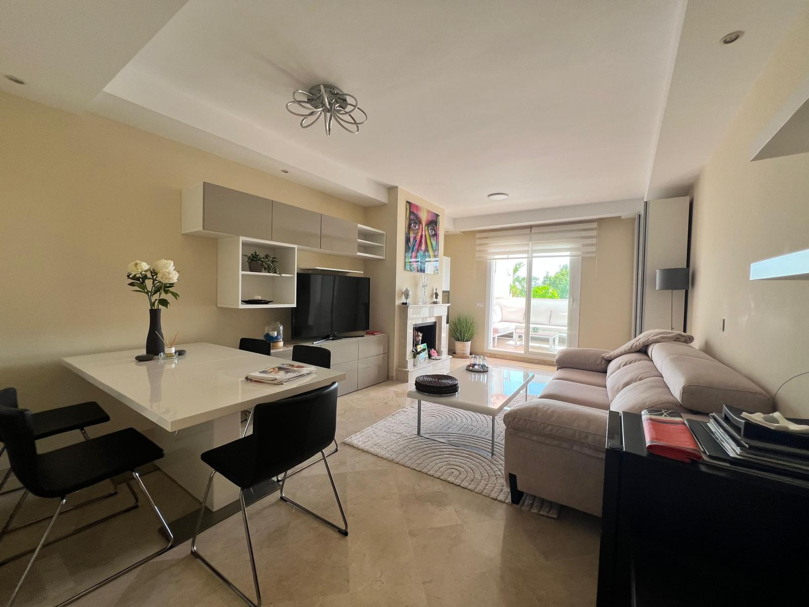 Combined living and dining room with sofa, coffee table, white dining table, and balcony access.