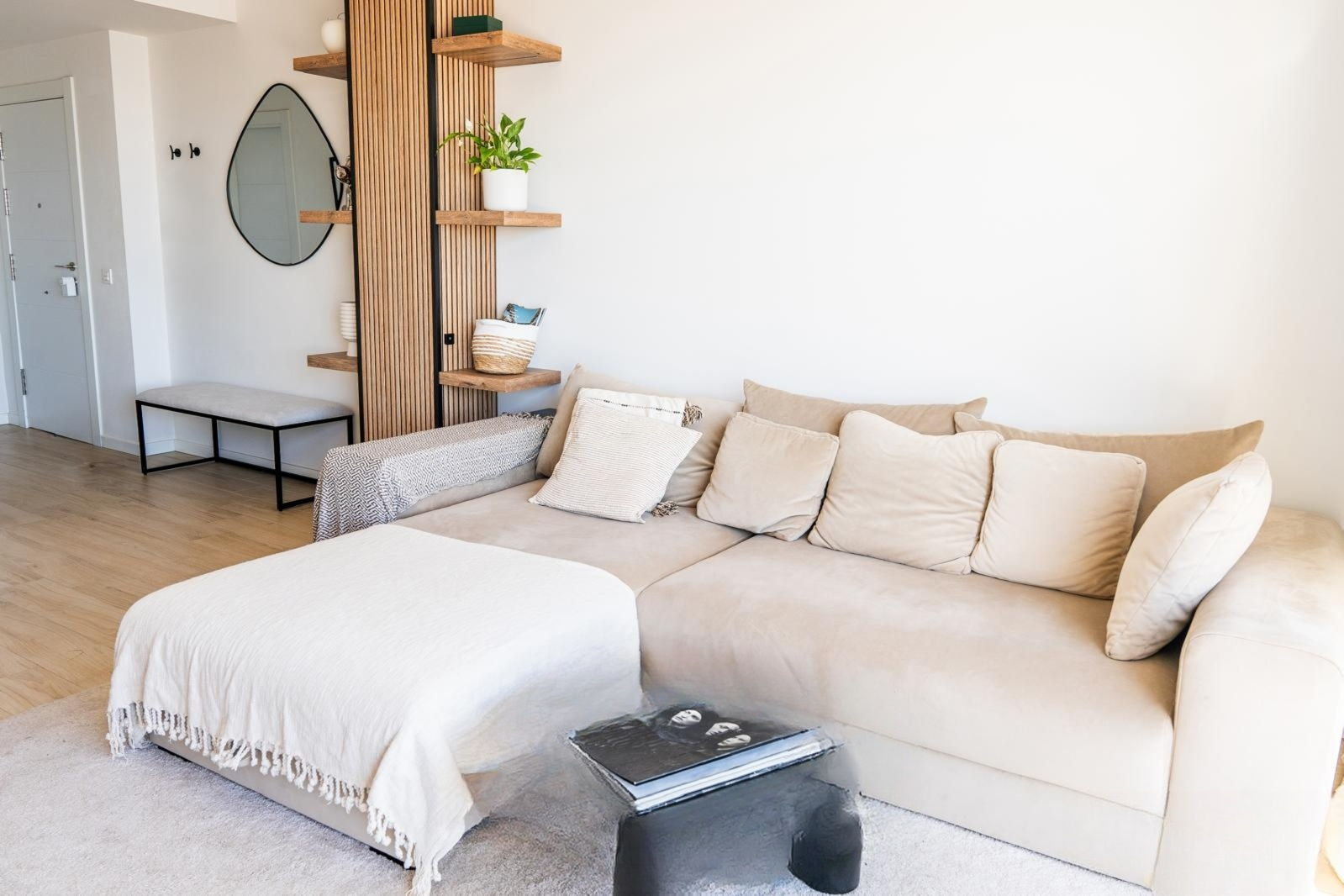 View of living room with beige sectional sofa, wood room divider, and entrance door to left.