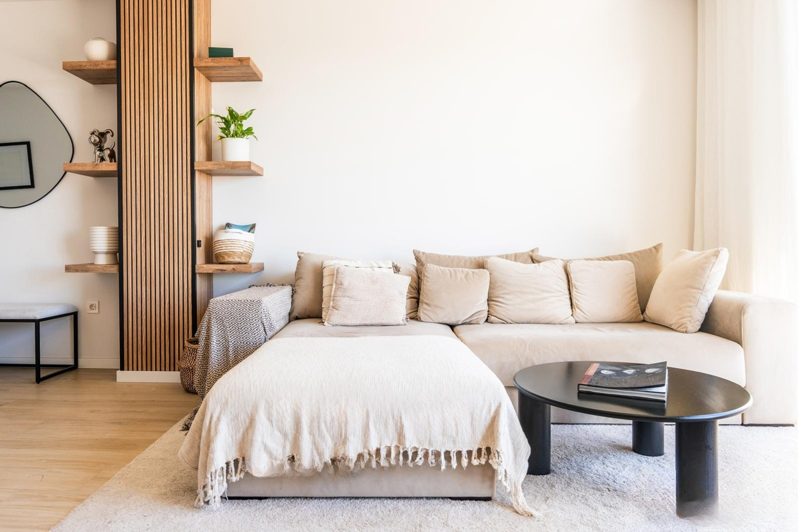 Living room with a beige sectional sofa, black coffee table, and wood slat room divider.