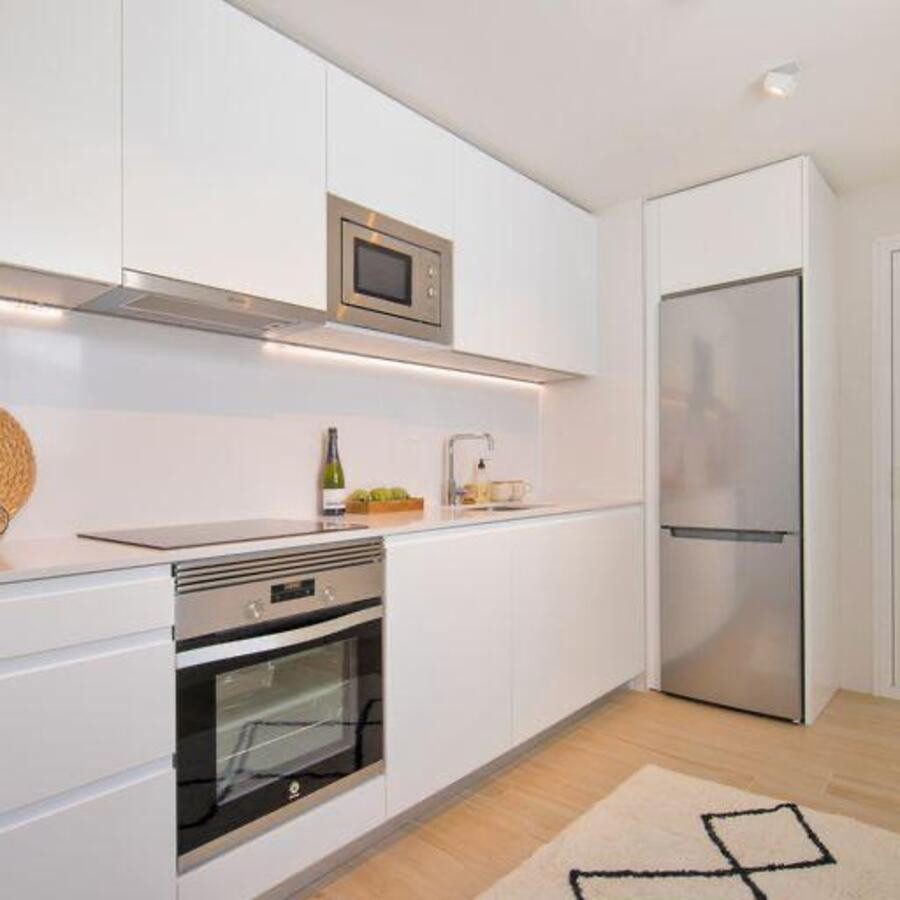 Modern kitchen with white cabinetry, stainless steel appliances, and a light wood floor.