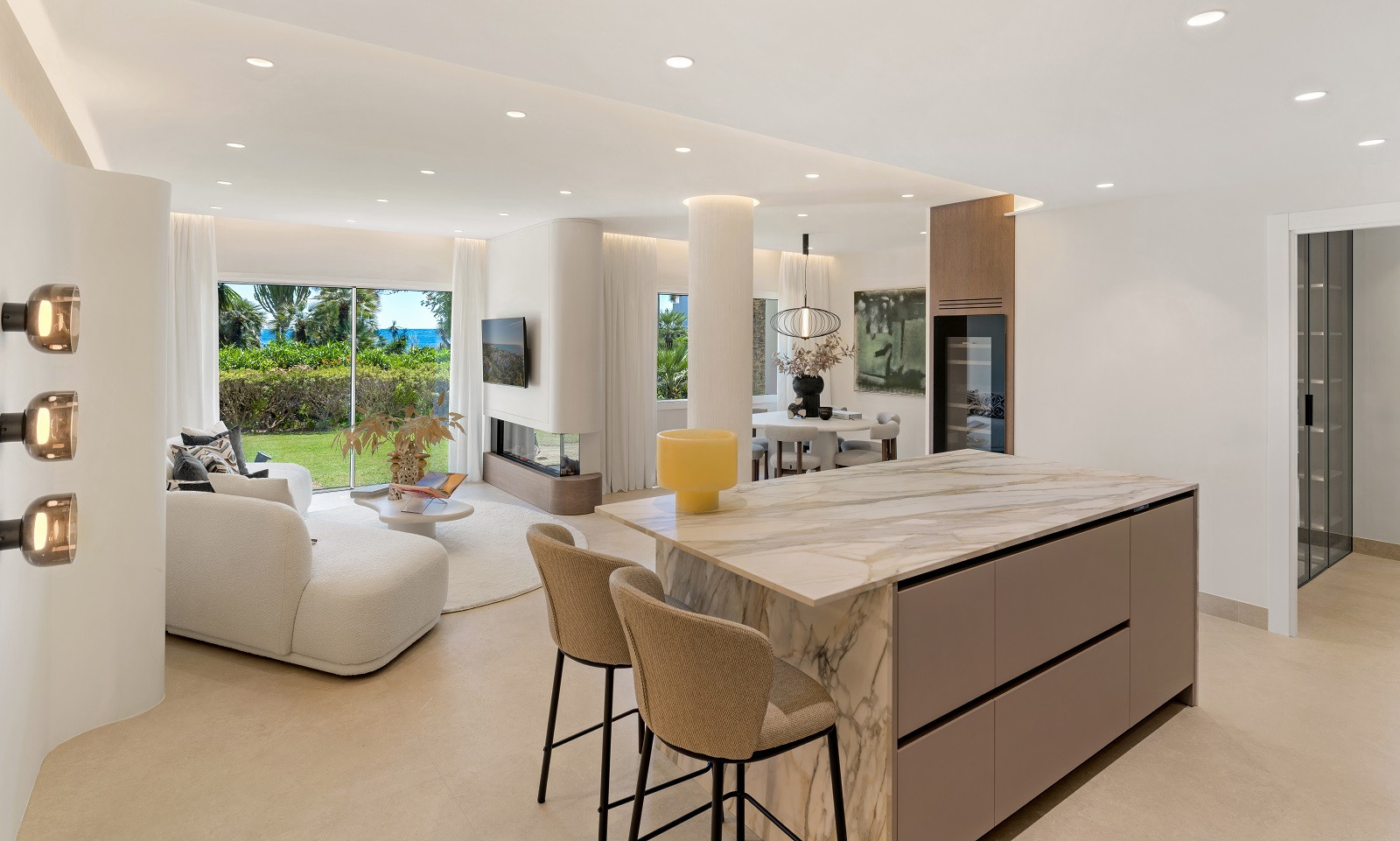 Open plan living space with a white sectional sofa, fireplace, and kitchen island in the foreground.