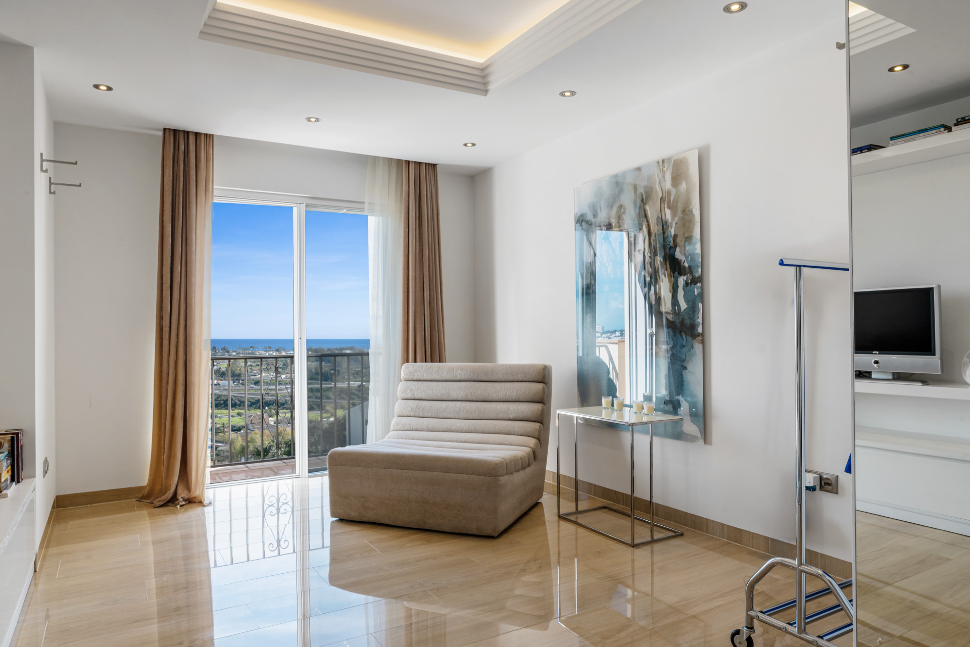Bedroom or lounge area with a modern chair, high ceilings, and a balcony with a sea view.