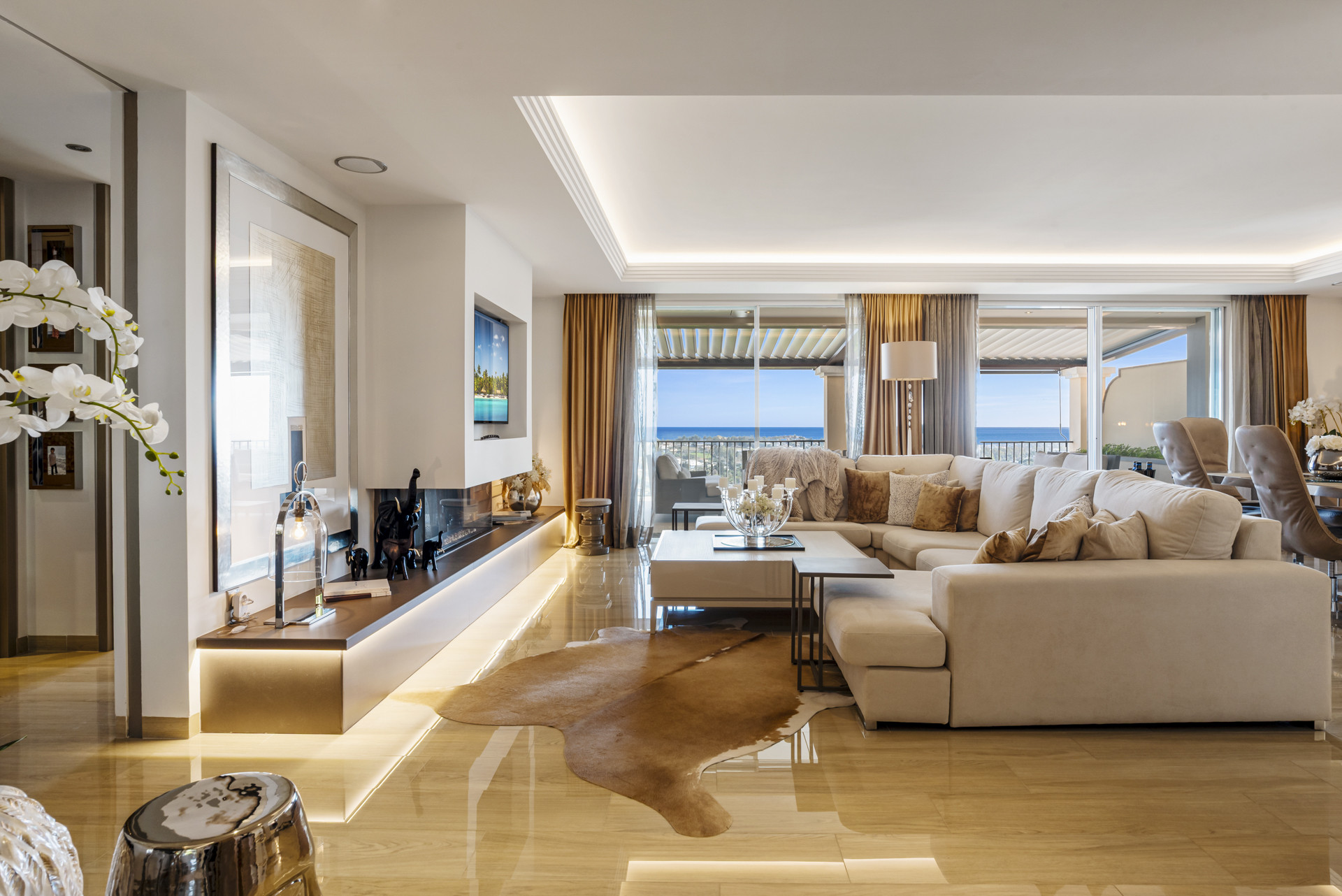 Spacious living room with a long linear fireplace, large sectional sofa, and ocean view.