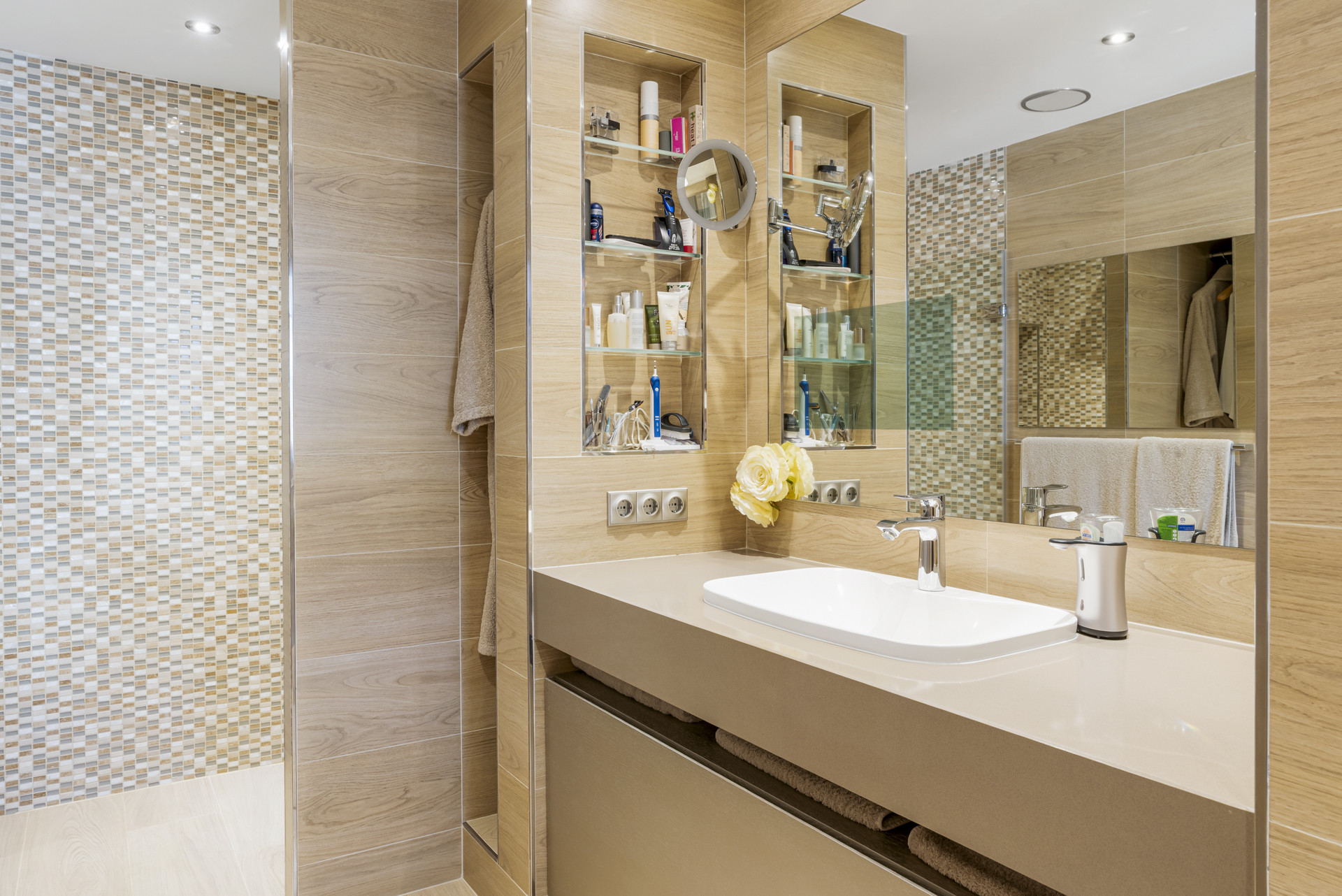 Modern bathroom with a single sink vanity, wall-mounted mirror, and a tiled shower stall.