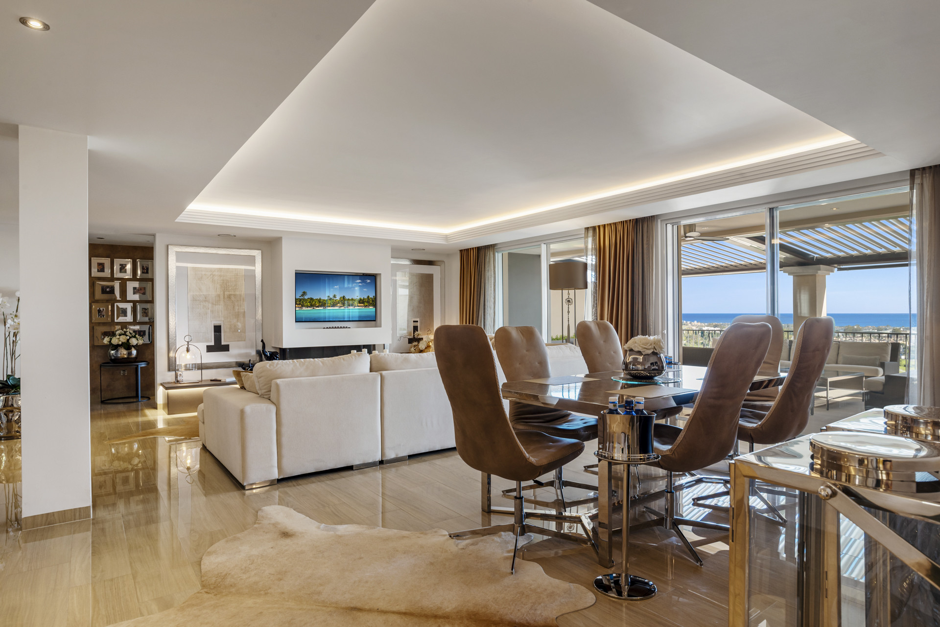Open plan living and dining area with large sofa, dining table, and sea view balcony.