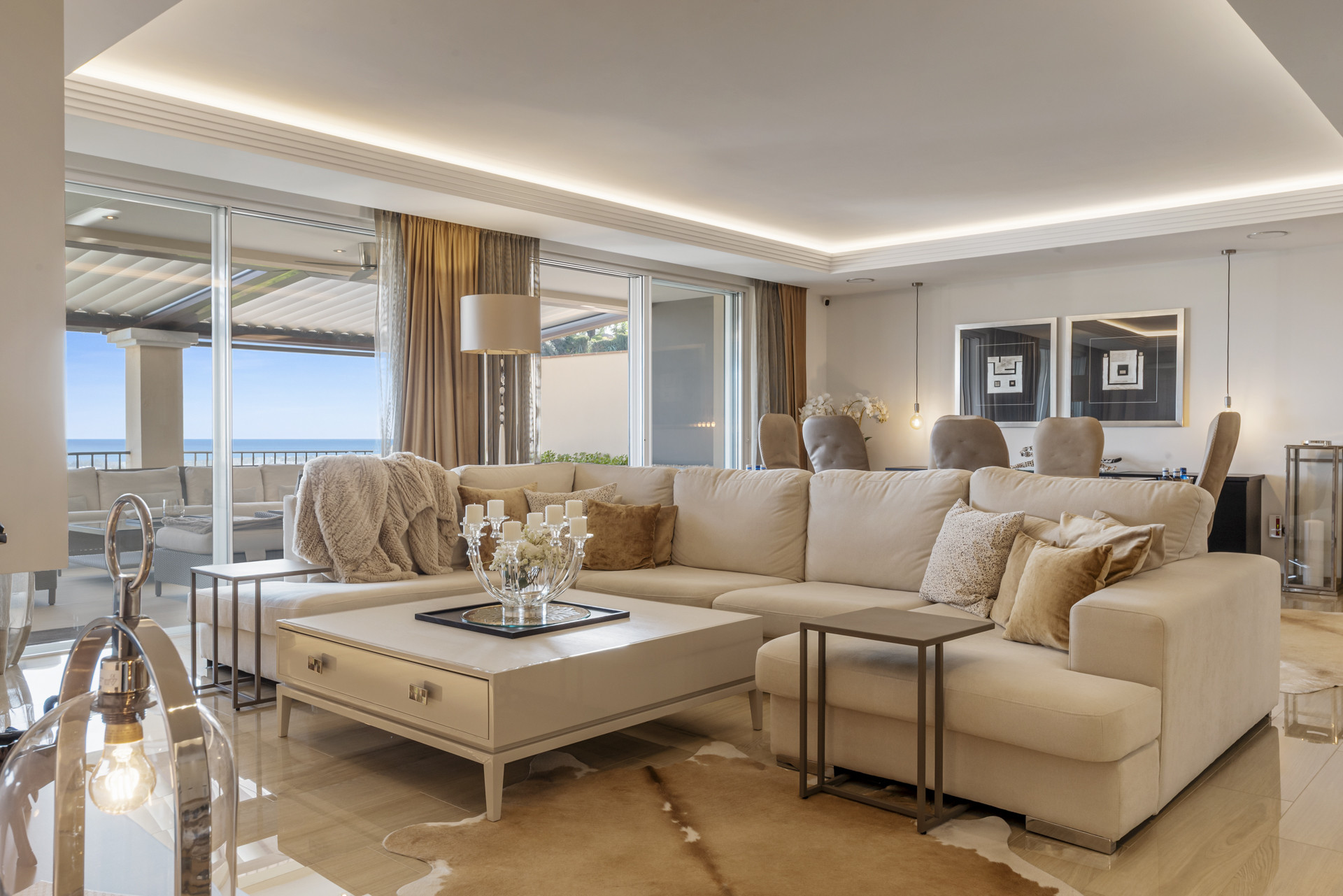 Elegant living room with a large L-shaped sofa, coffee table, and sliding glass doors to a balcony.